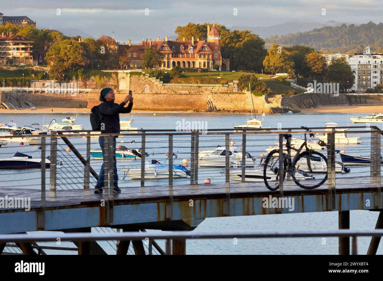 Turista con bicicleta en el embarcadero del Club Nautico, Puerto de Donostia, Bahia de La Concha, Palacio Miramar, Donostia, San Sebastian, Pais Vasco, España. Stock Photo