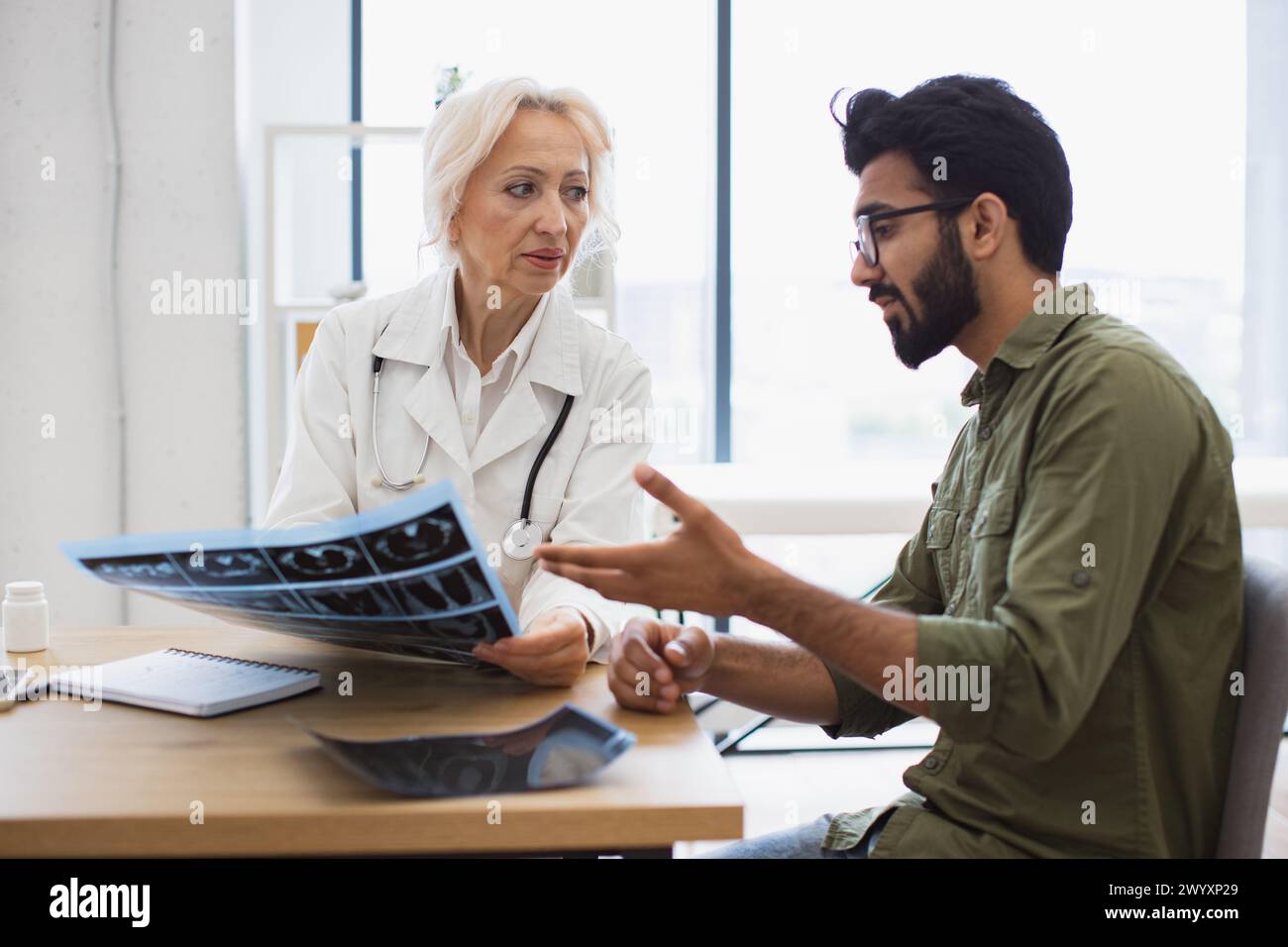 Family doctor examining diagnostic test results while developing treatment plan. Stock Photo