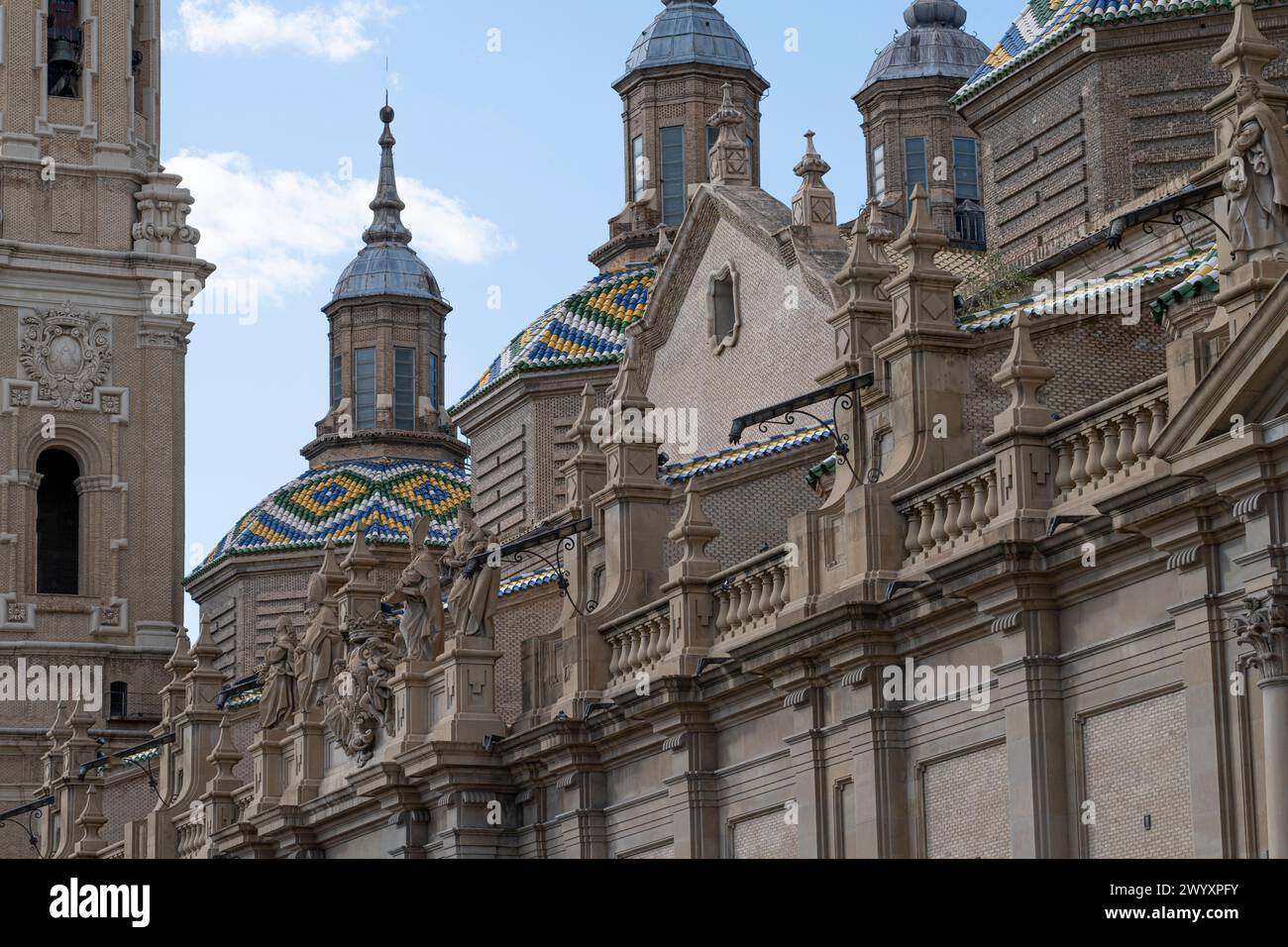 Grand front view of Basilica del Pilar's Baroque facade, adorned with sculptures, under a vibrant blue sky Stock Photo