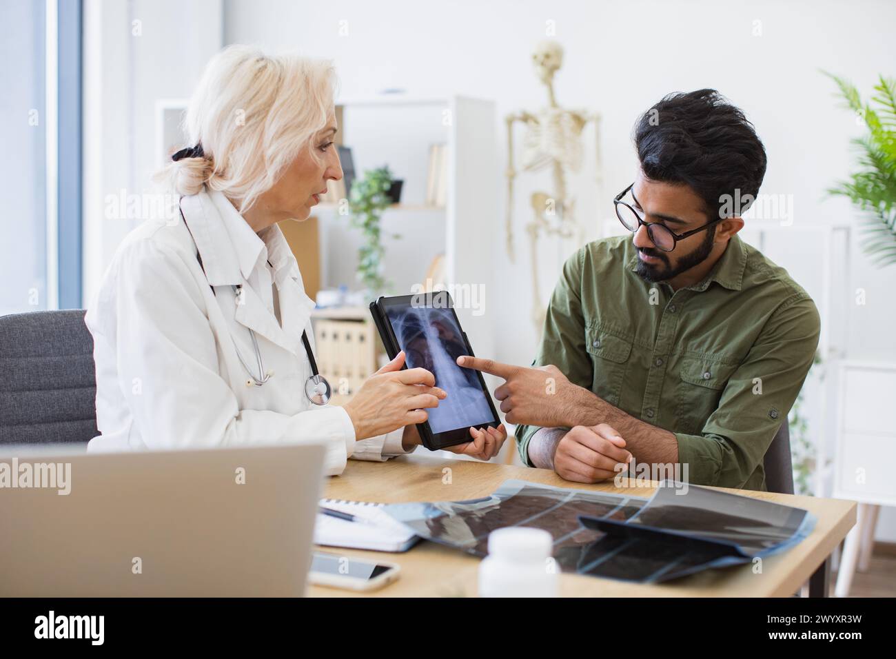 Family doctor examining diagnostic test results while developing treatment plan. Stock Photo