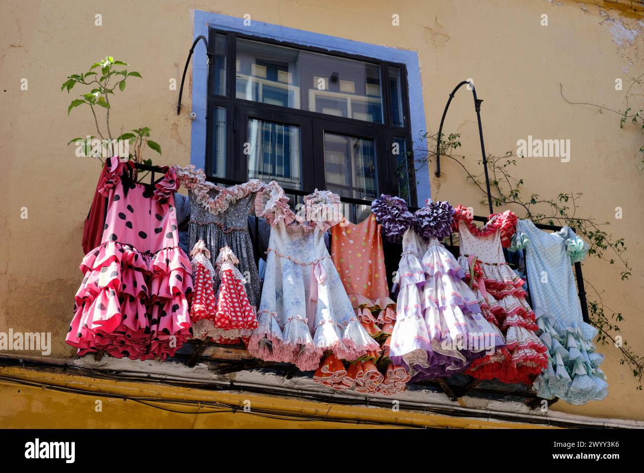 Traditional flamenco dresses costumes hanging on a spanish andalusian house balcony facade in Málaga, Spain. Stock Photo