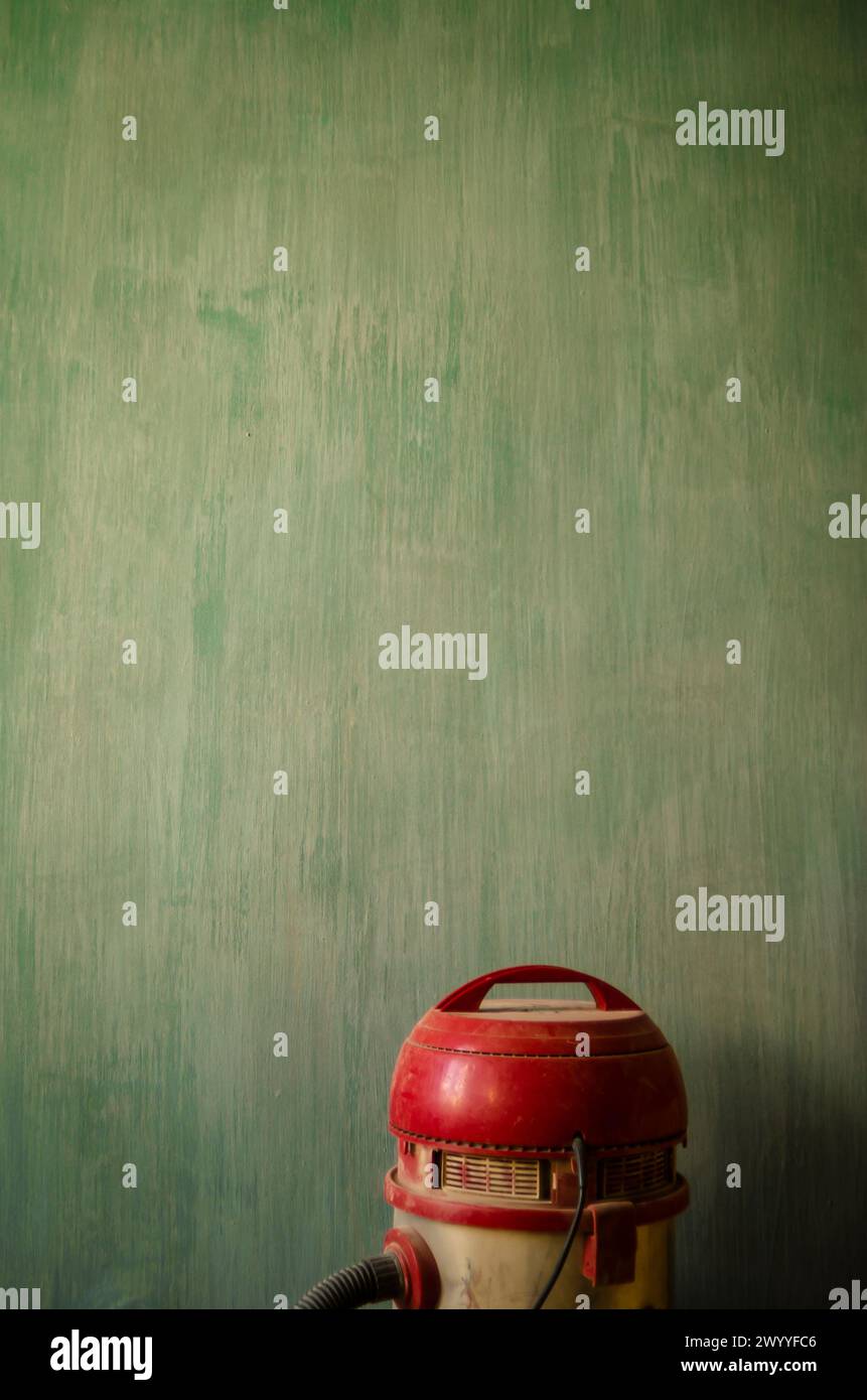 artistic background, red vacuum cleaner on a green textured wall, resembles a movie character Stock Photo