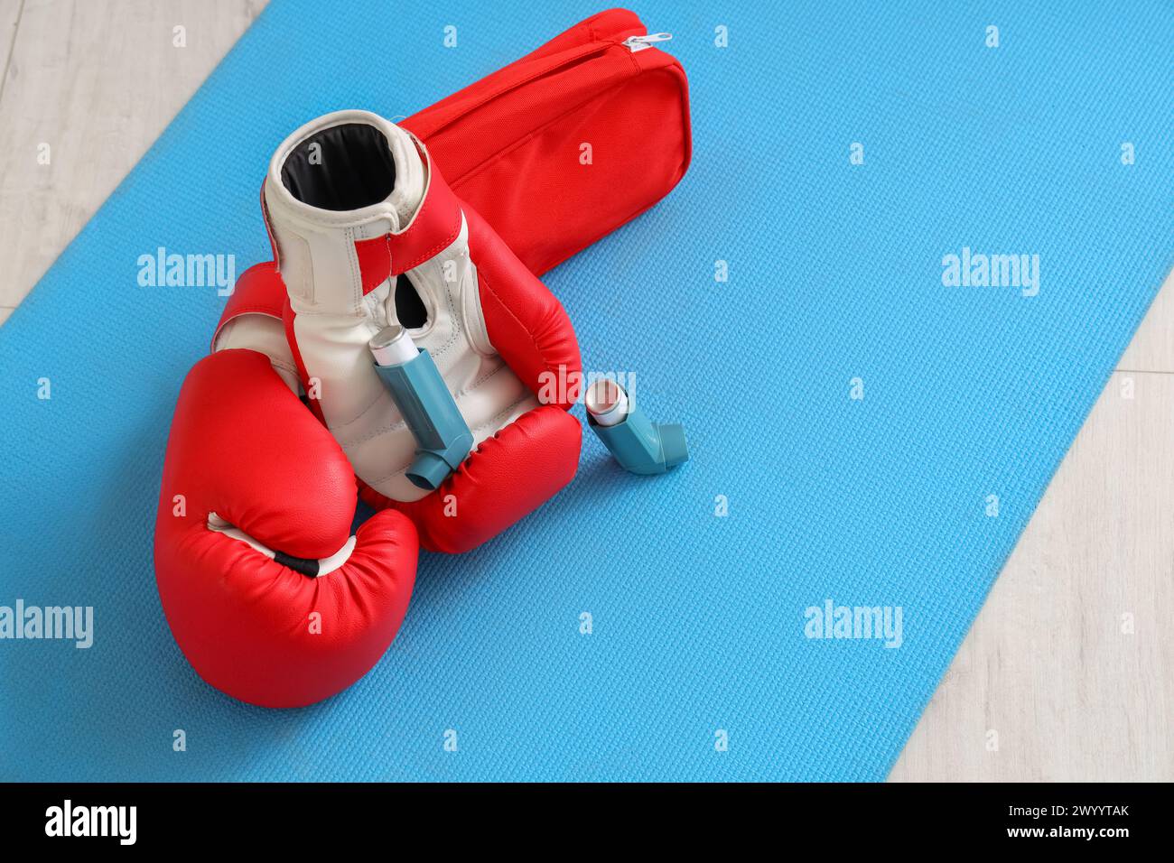 Asthma inhalers with boxing gloves and first aid kit on mat in gym ...