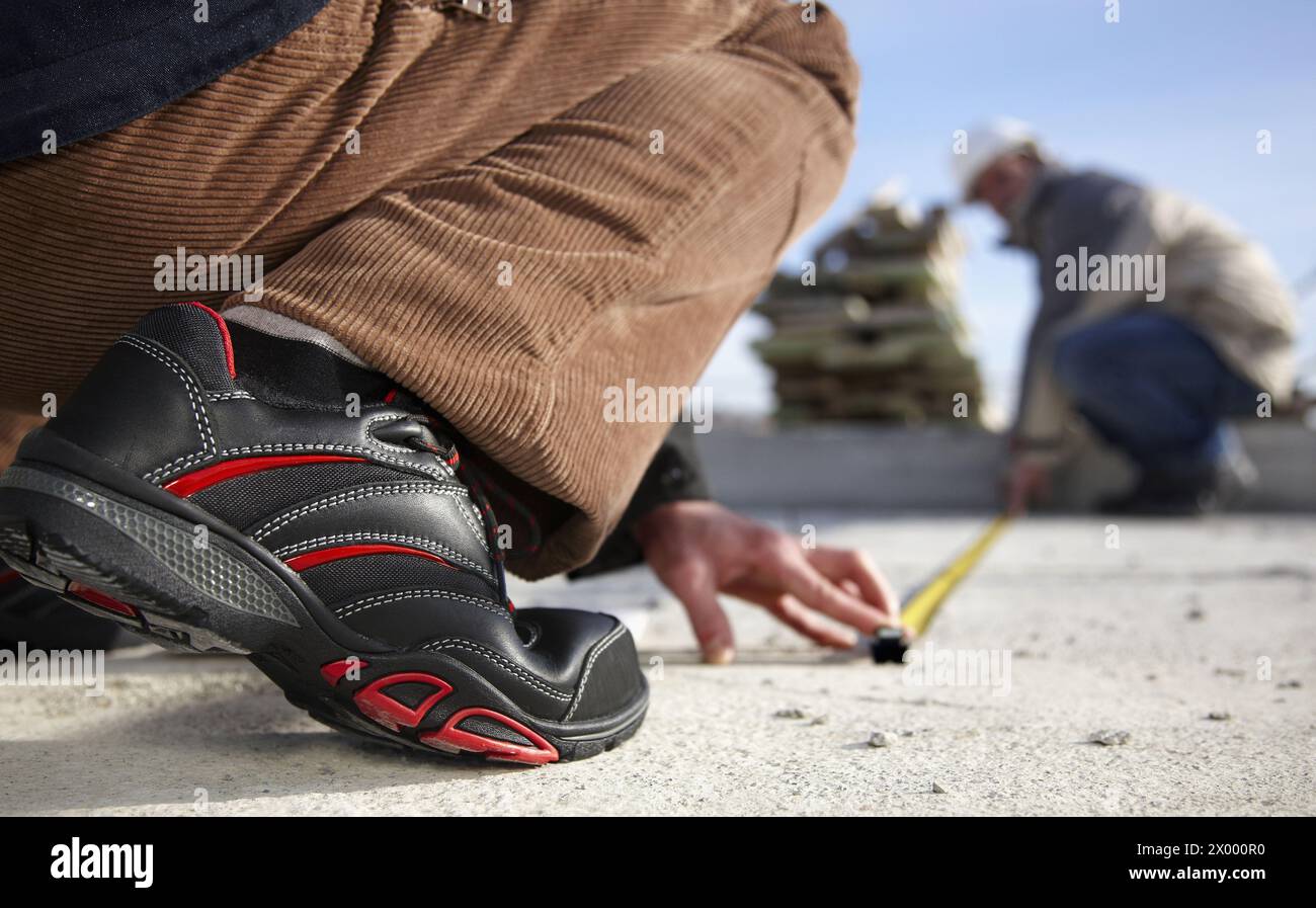 Construction workers measuring, personal protective equipment, housing construction. Stock Photo