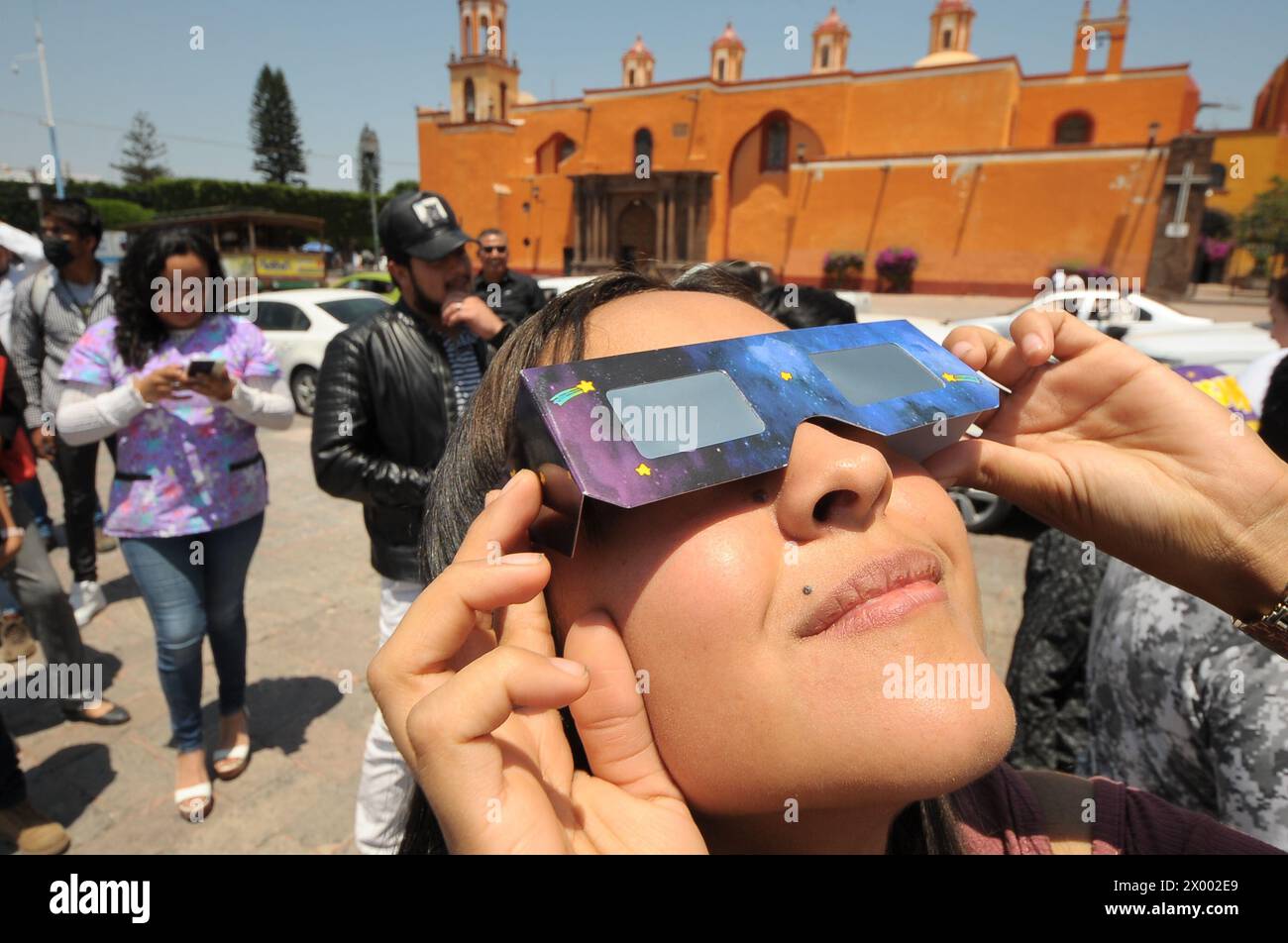 A woman watches the solar eclipse through a special viewing glasses ...