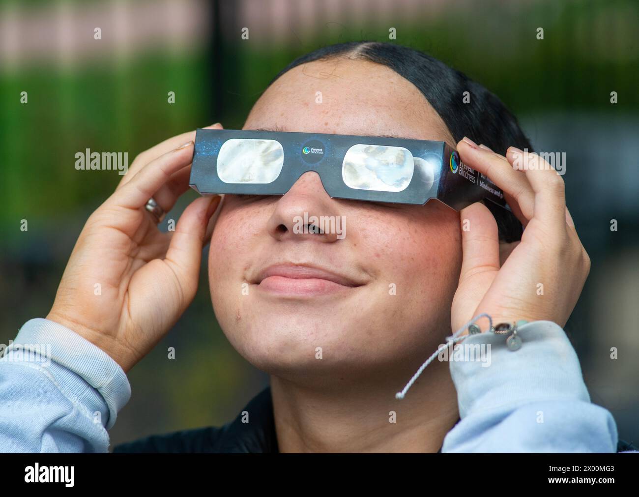 Angel Carr of Levittown, Pa. holds solar eclipse protective glasses up
