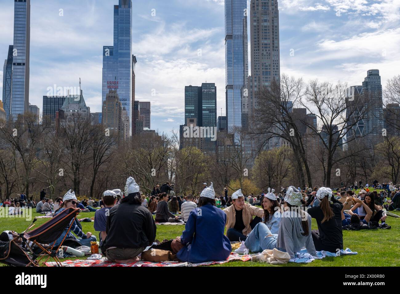 New York, United States. 08th Apr, 2024. People wearing tin foil hats enjoy the eclipse with a city skyscraper view facing south. New Yorkers gathered in Central Park to view the solar eclipse. The sun was eclipsed by the moon by 90%, just shy of totality. The last solar eclipse in New York City was in 2017 reaching 70%. The next solar eclipse for the city will be in 2045 at only 50%. New Yorkers will have to wait until May, 2079 for totality. Credit: SOPA Images Limited/Alamy Live News Stock Photo