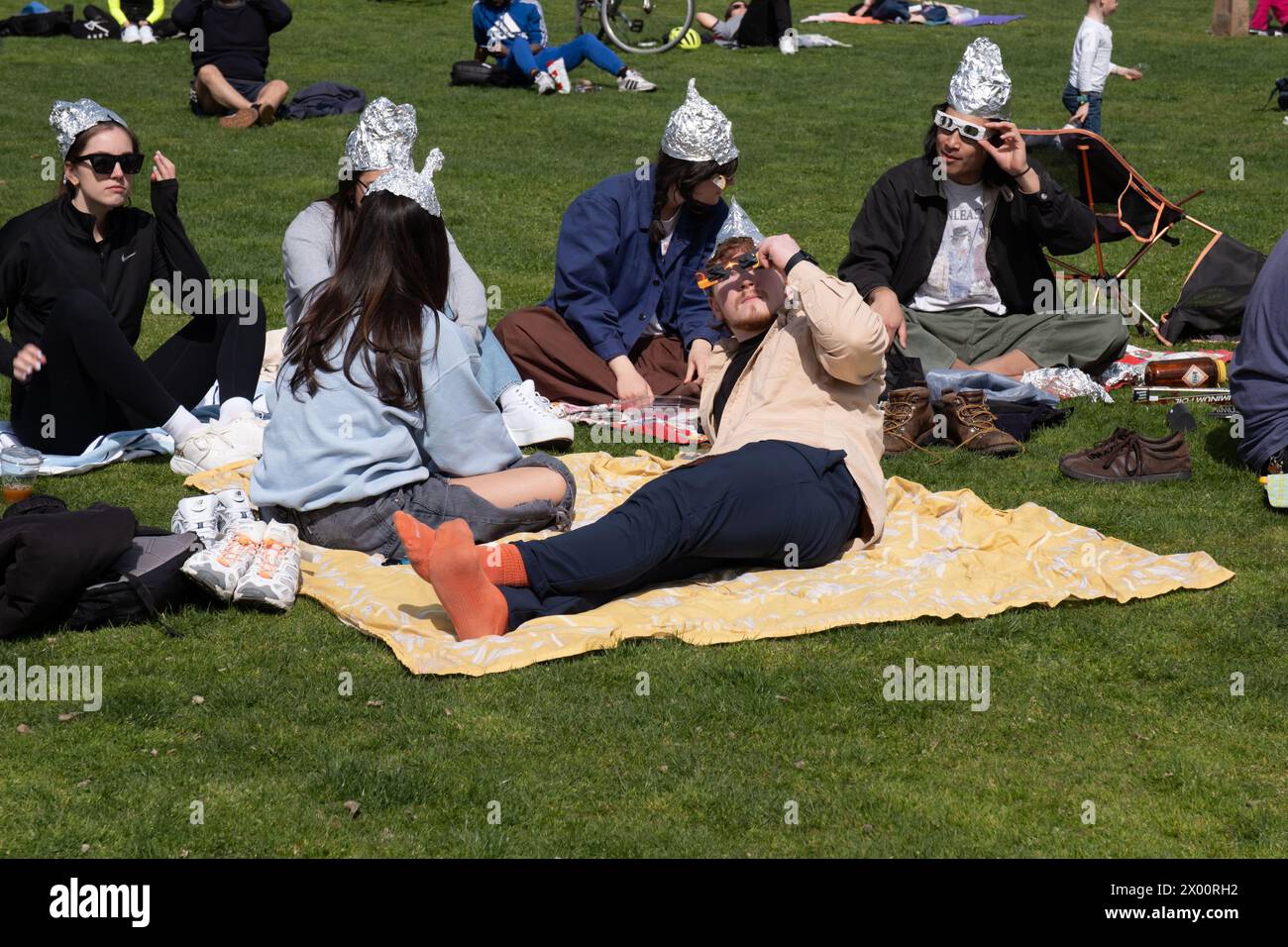 New York, United States. 08th Apr, 2024. A group of people wearing tin foil hats watches the eclipse while sitting on the grass. New Yorkers gathered in Central Park to view the solar eclipse. The sun was eclipsed by the moon by 90%, just shy of totality. The last solar eclipse in New York City was in 2017 reaching 70%. The next solar eclipse for the city will be in 2045 at only 50%. New Yorkers will have to wait until May, 2079 for totality. Credit: SOPA Images Limited/Alamy Live News Stock Photo