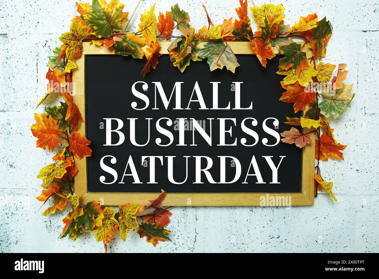 Small Business Saturday typography text on wooden blackboard hanging with maple leaf decoration Stock Photo