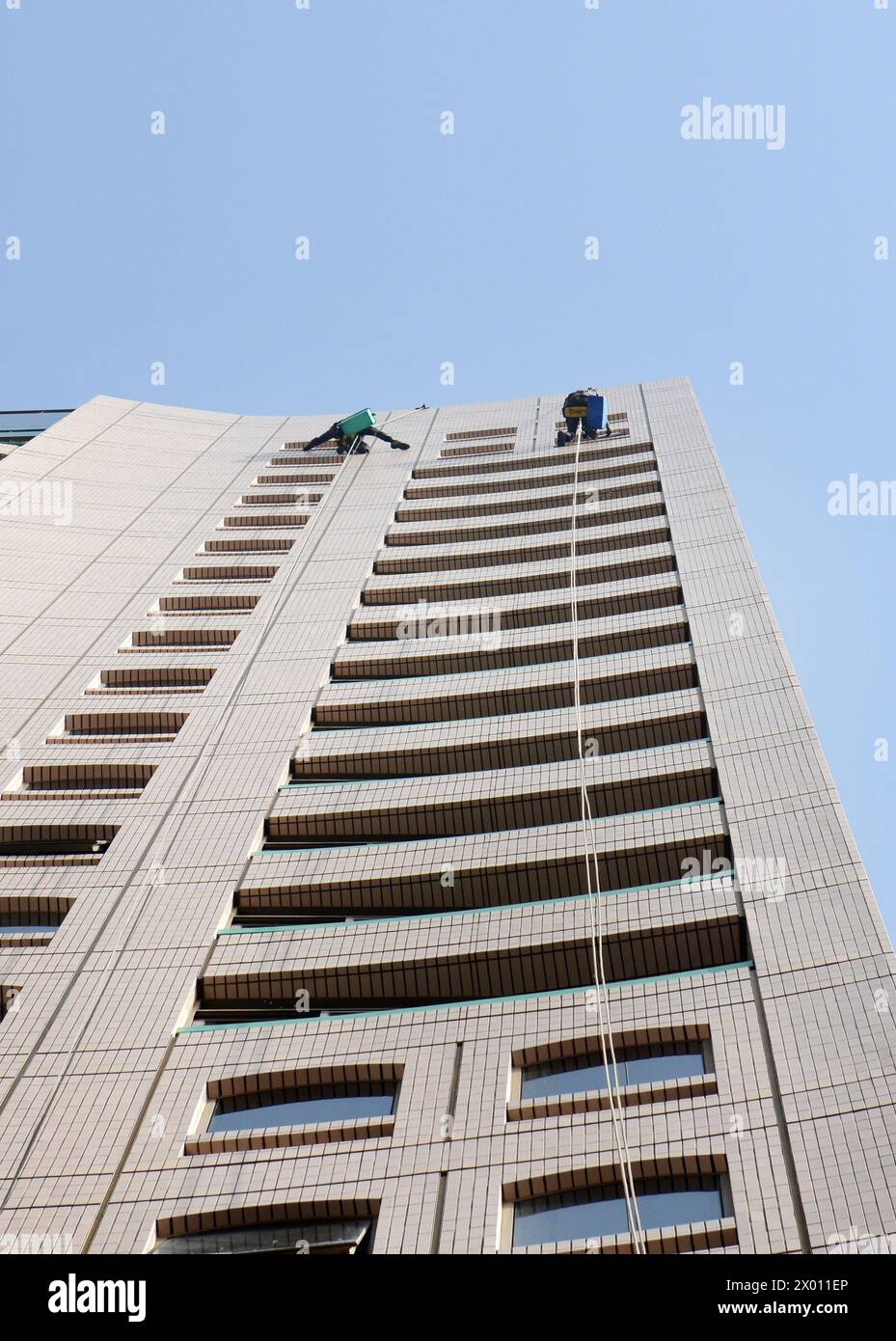 Rope access window cleaners cleaning windows of a tall building in Deira, Dubai, UAE. Stock Photo