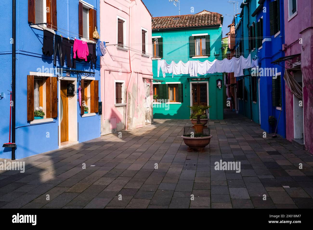 Colourfully painted houses with laundry put up on washing lines on the island of Burano. Stock Photo