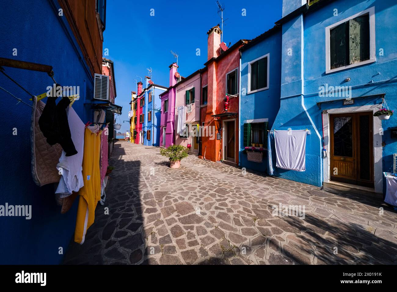 Colourfully painted houses with laundry put up on washing lines on the island of Burano. Stock Photo