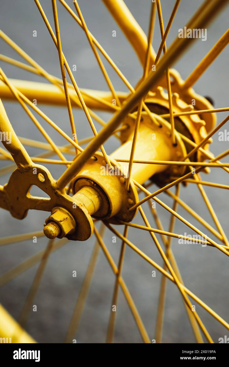 Old bicycle wheel painted in vibrant yellow color, selective focus Stock Photo