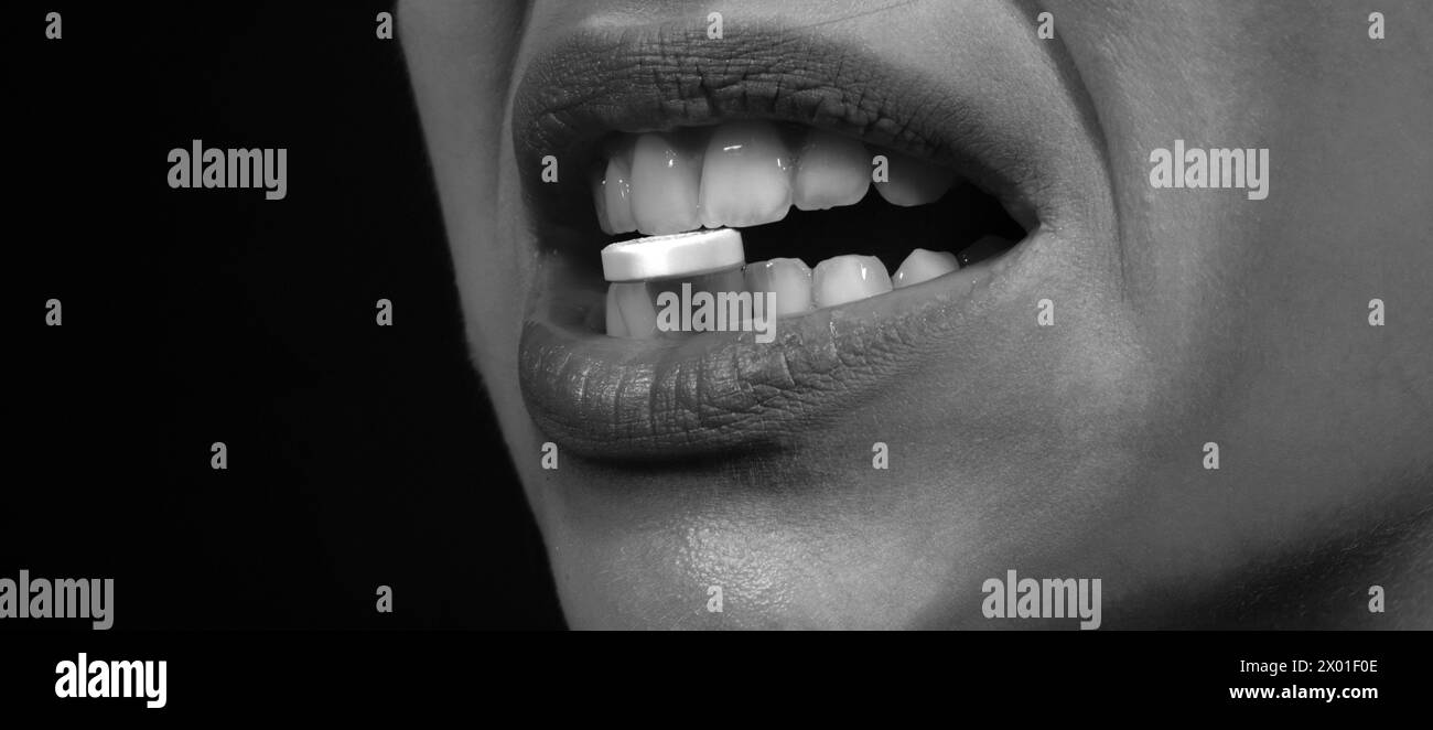 Close-up of pill in woman teeth. Lips holds pills in mouth. Close up of ...