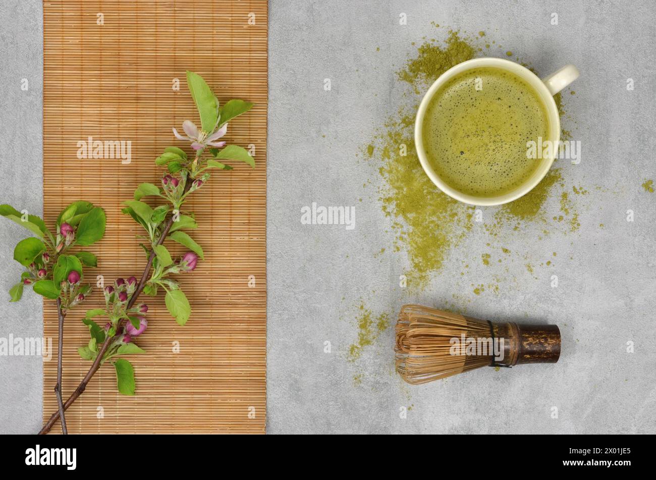 Matcha - green japanese tea, bamboo whisk and blooming twig with leaves. Top view. Stock Photo