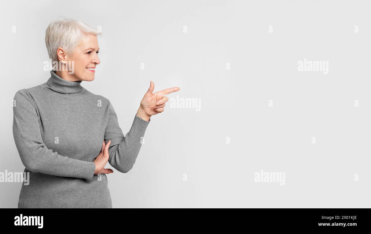 Senior lady gesturing to the side with a smile Stock Photo