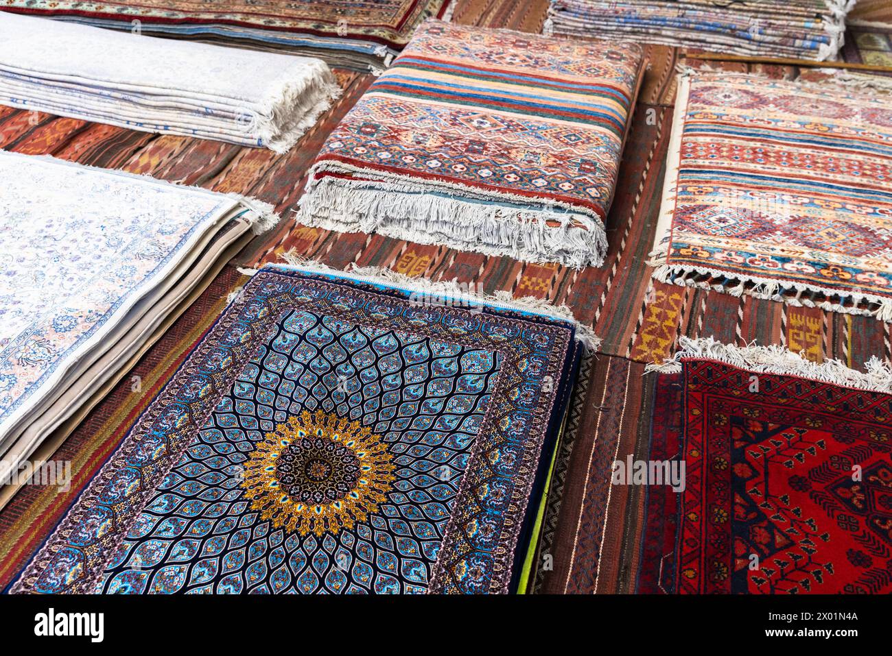 Assortment of oriental silk carpets for sale with colorful geometric patterns represented on historic Bukhara bazaar Stock Photo
