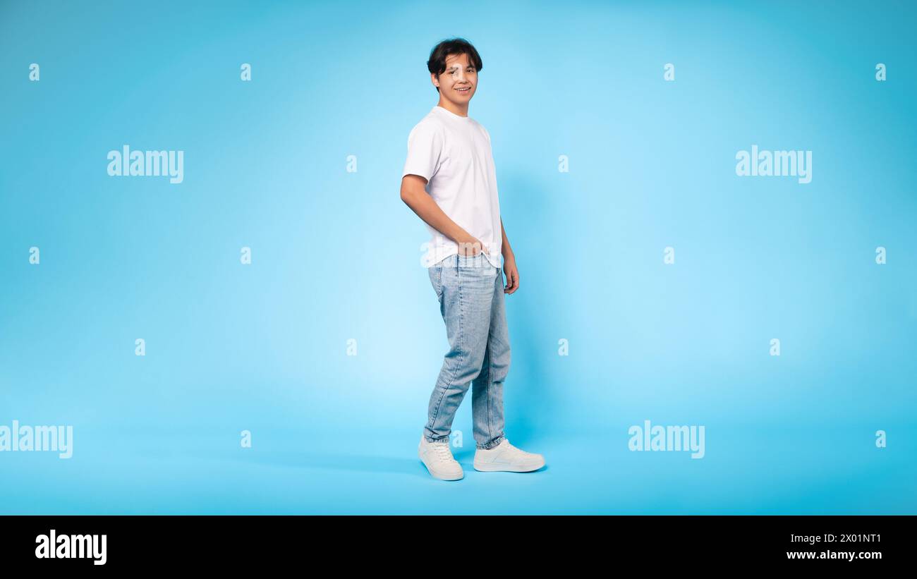 Casual dressed young guy standing profile, blue background Stock Photo