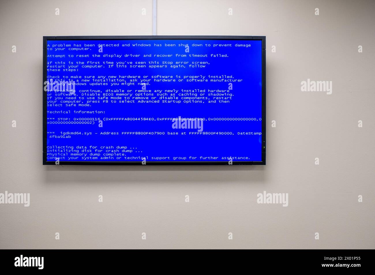 A blue screen of death message displayed on a wall-mounted monitor in an office. Stock Photo