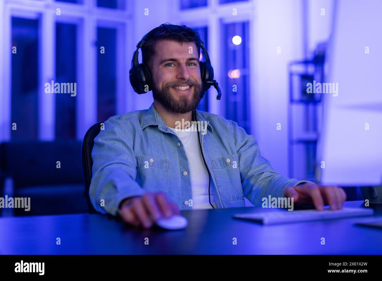 Smiling man using computer at night in neon light Stock Photo
