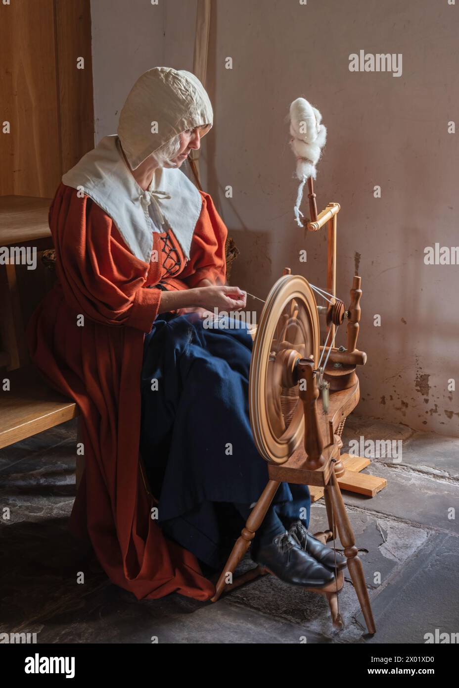 A maiden demonstrating the use of a spinning wheel at Tretower Court and Castle, Tretower, Powys, Wales, UK. Stock Photo