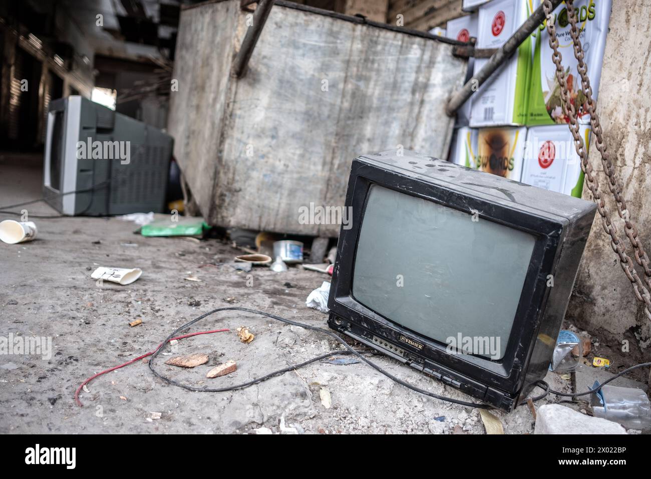MUHARRAQ, BAHRAIN - FEBRUARY 10, 2018: Defunct cathode ray tube television sets sit abandoned on a concrete floor by a dumpster with other trash. Stock Photo