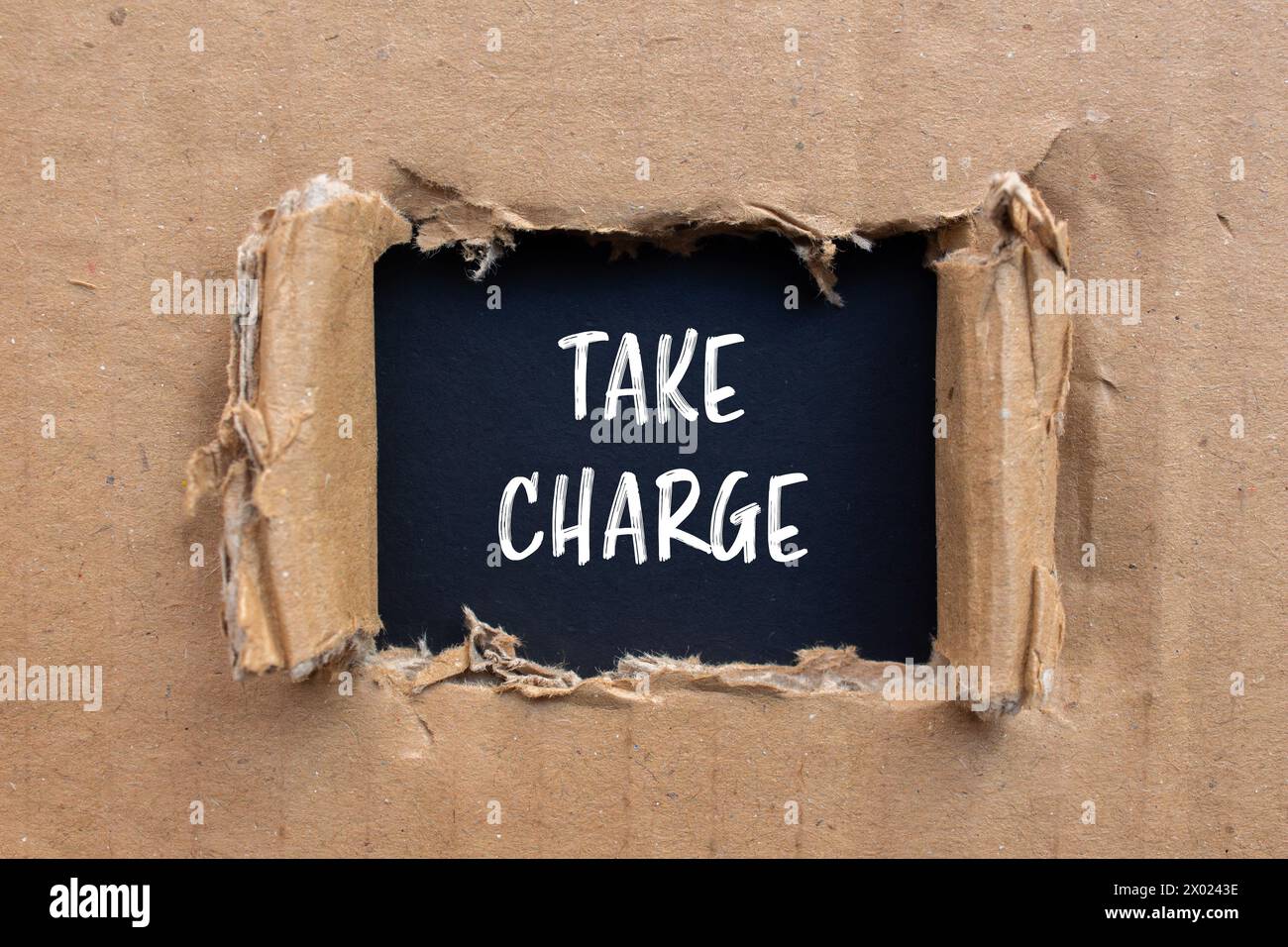 Take charge words written on ripped paper with black background. Conceptual take charge symbol. Copy space. Stock Photo