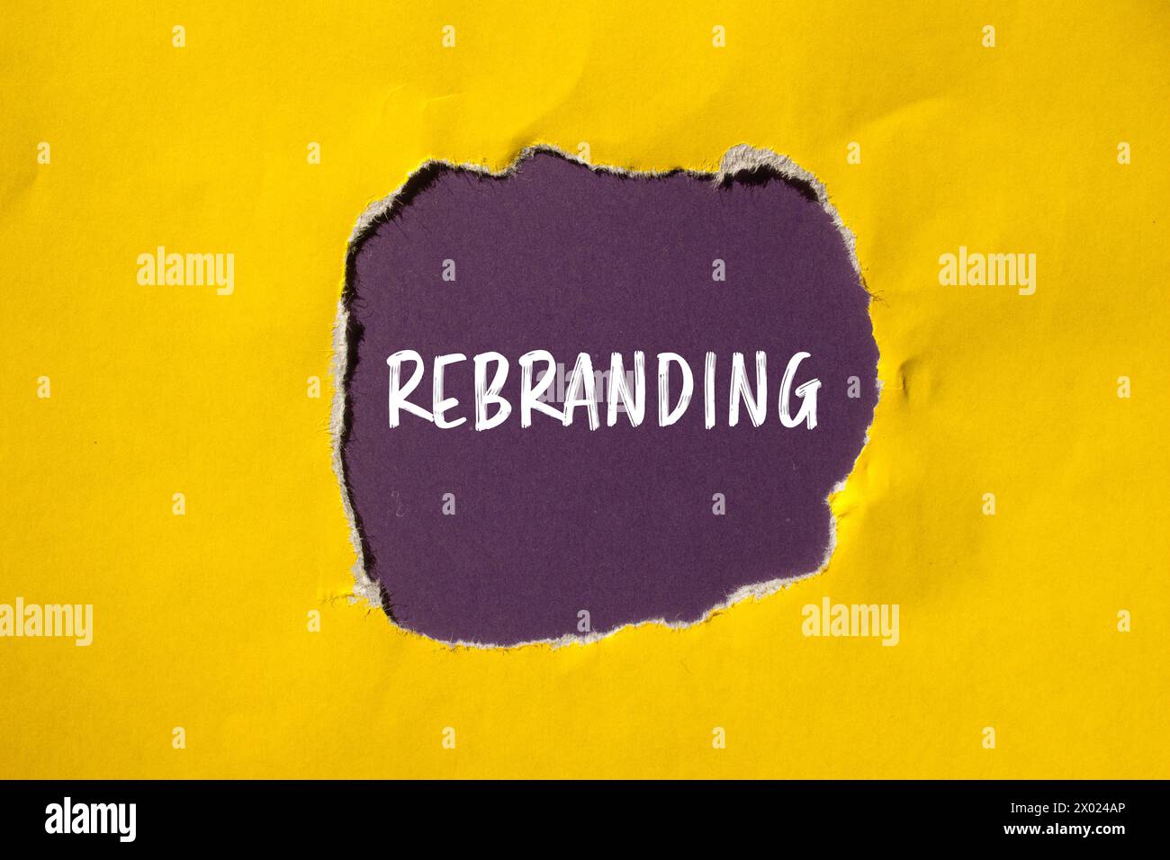 Rebranding word written on ripped yellow paper with purple background ...