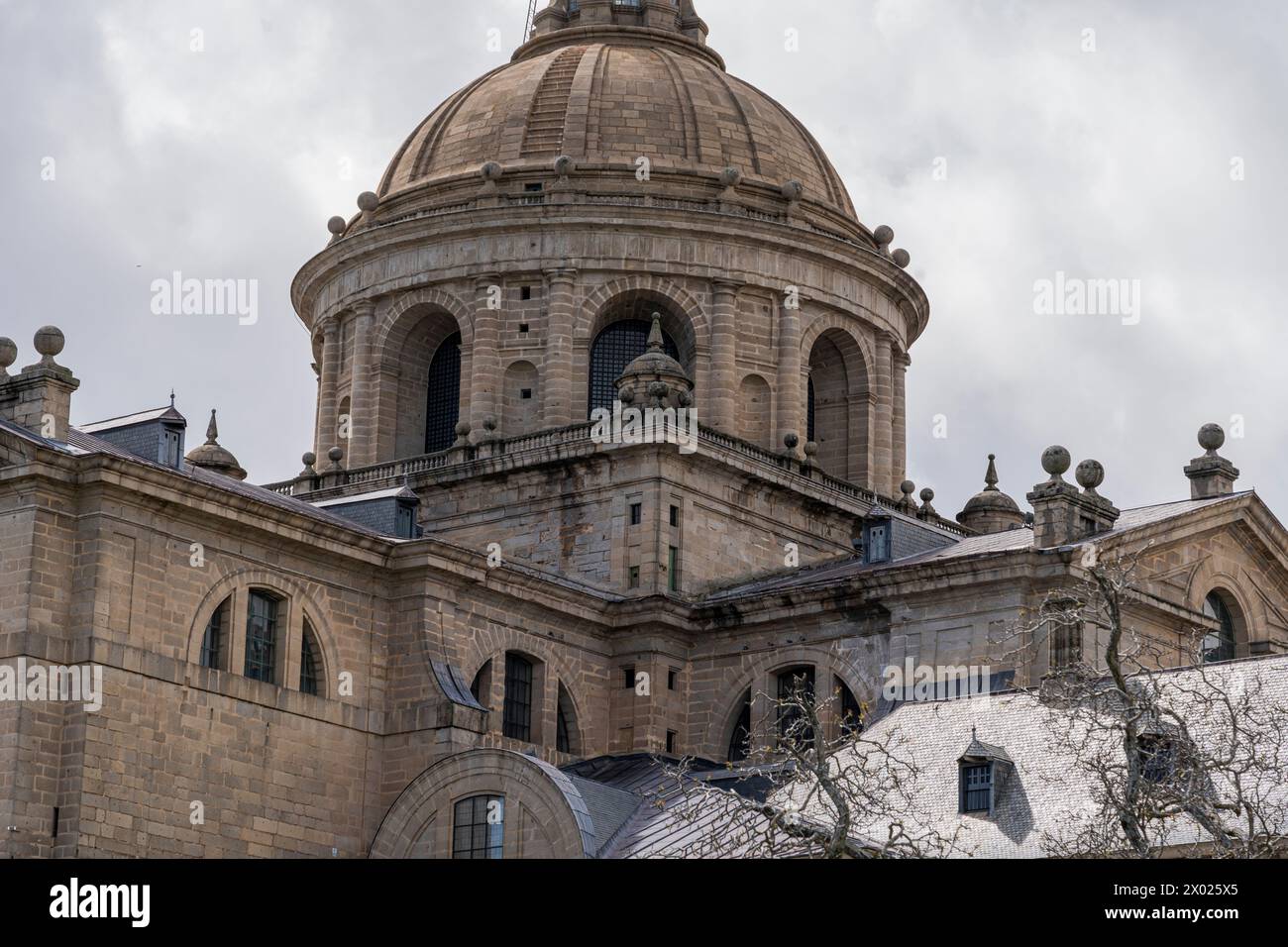 The grand dome of the Escorial Monastery near Madrid, Spain, rises majestically against a backdrop of dynamic clouds. Stock Photo
