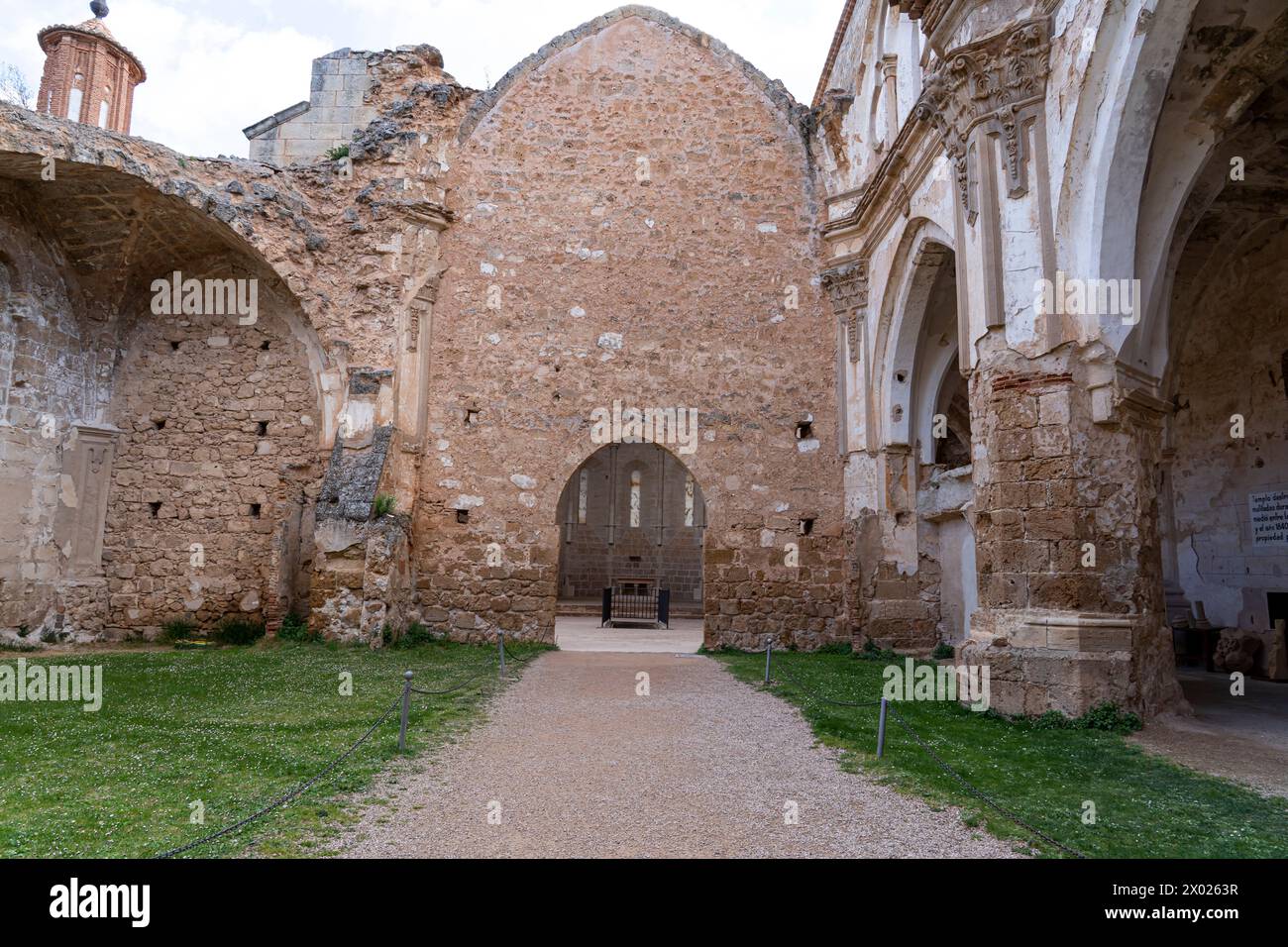 A vertical shot capturing the intricate facade of the weathered ruins of the Monasterio de Piedra's church against a cloudy sky. Stock Photo