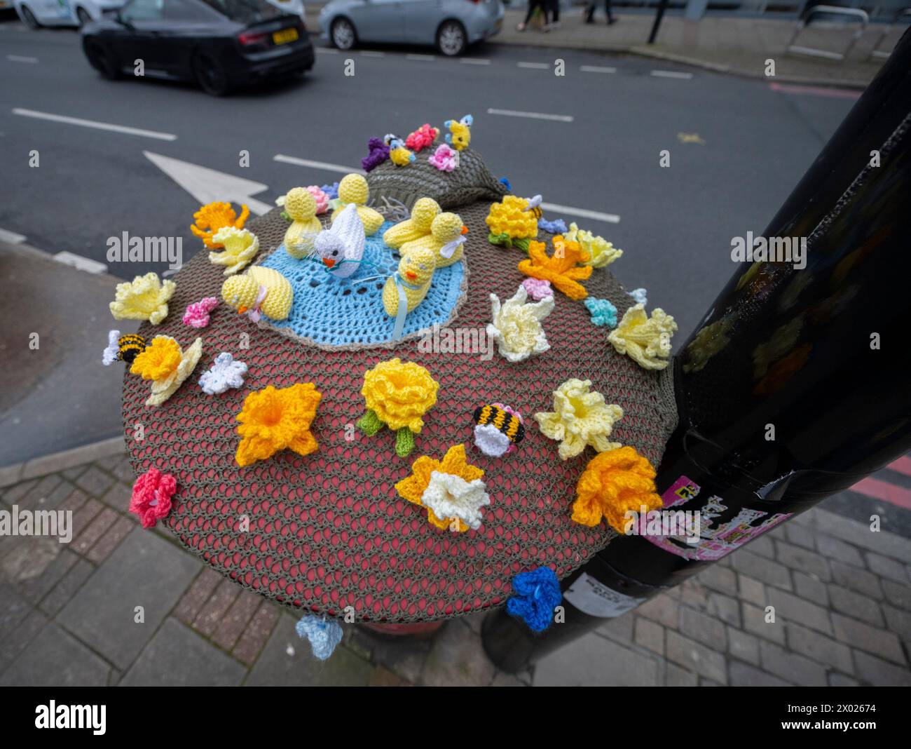 Morden, London, UK. 9th Apr, 2024. A colourful hand knitted Easter display tops a somewhat tatty post box on a busy urban street in south west London. Credit: Malcolm Park/Alamy Live News Stock Photo