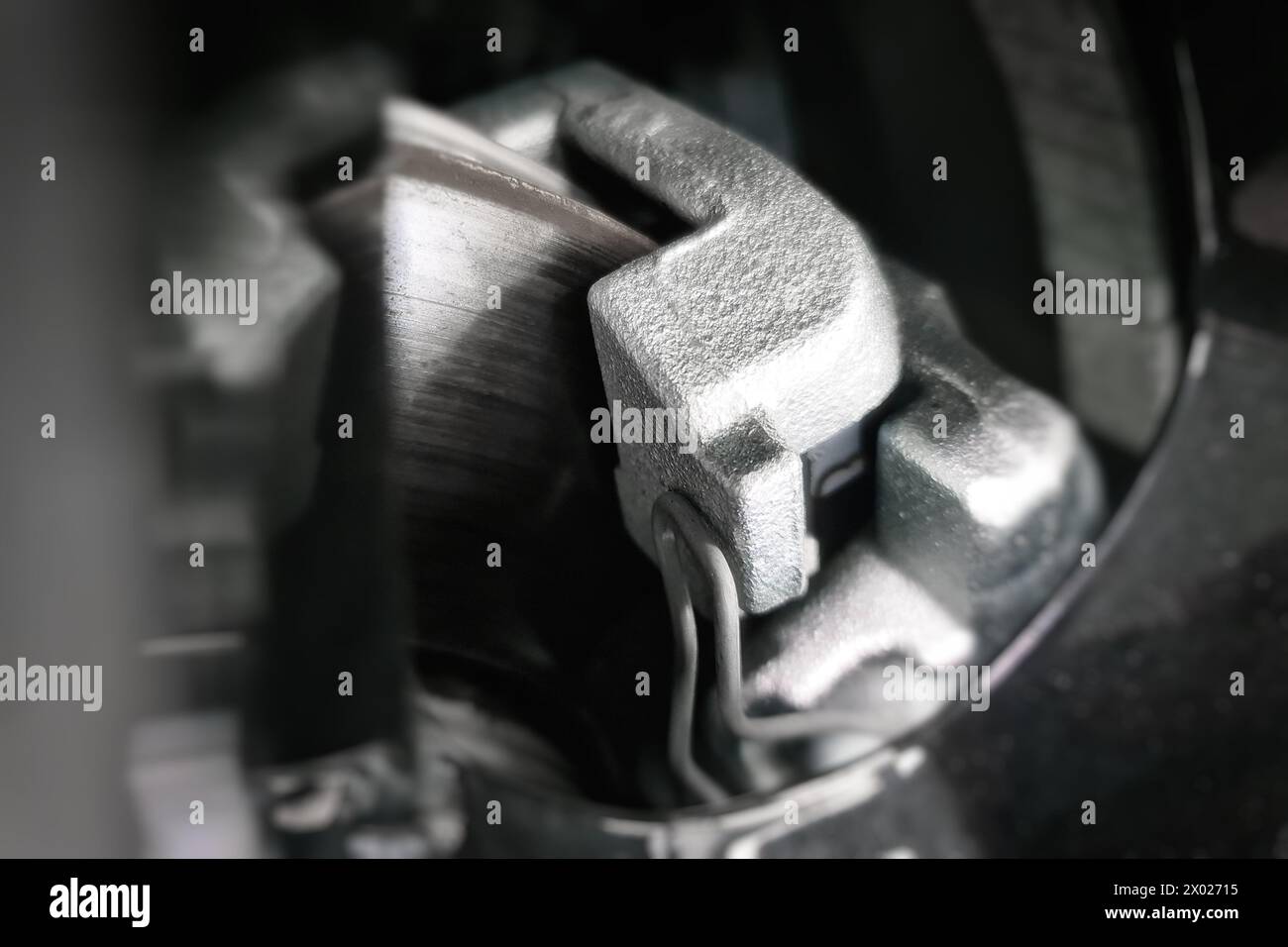Brake disc and caliper with brake pads visible through the car's alloy wheel. Selective soft focus Stock Photo