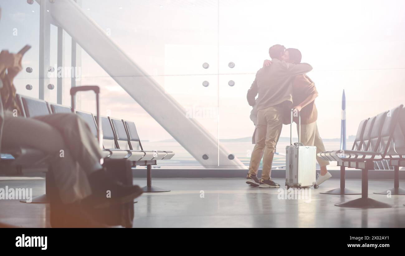 Airport Terminal Family Reunion: Caring Father Meets His Cute Little Daughter and Beautiful Wife at the Boarding Lounge of Airline Hub. He Picks Up and Dances with Lovely Child and Hugs His Partner Stock Photo