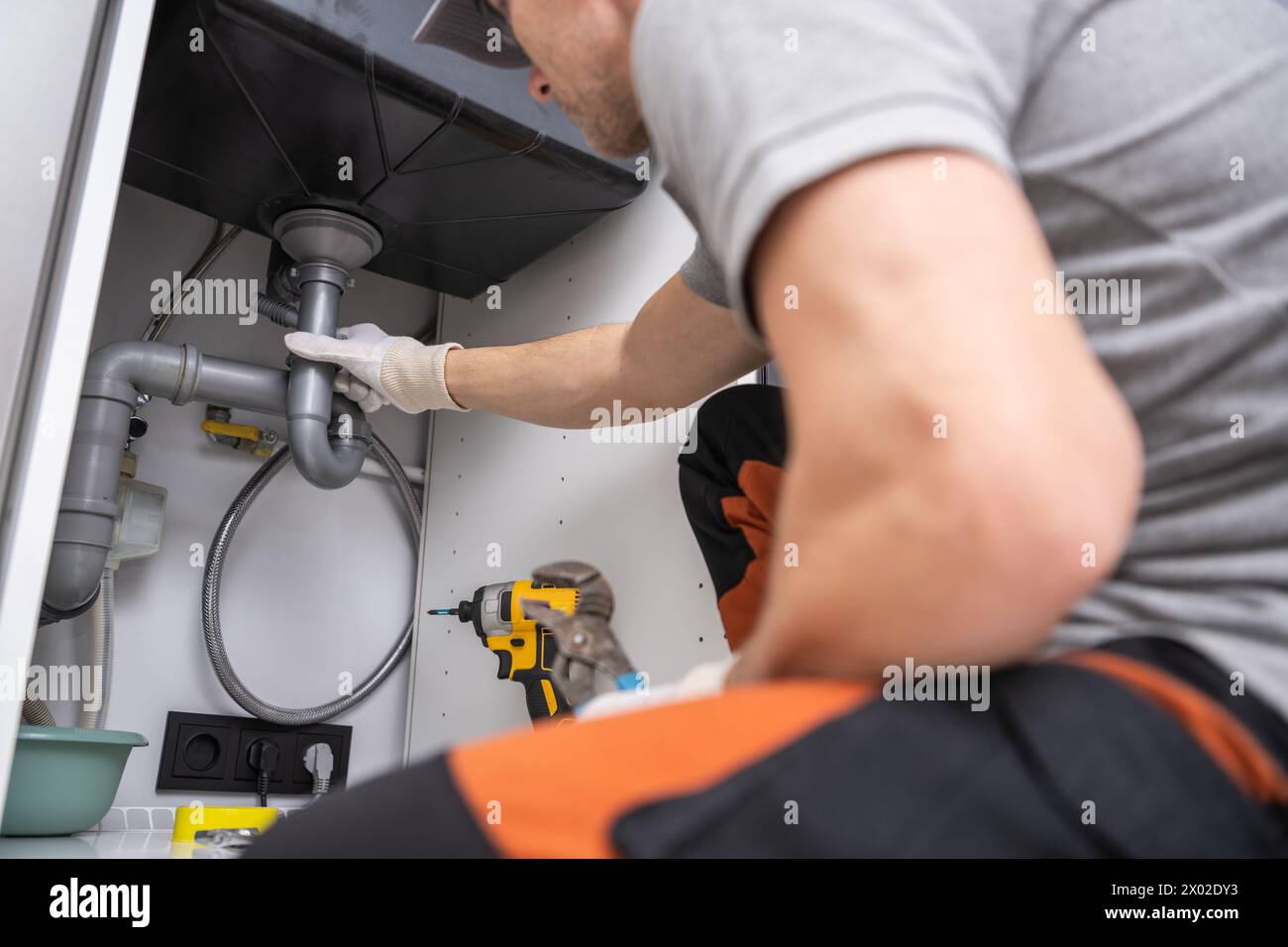 Caucasian Plumber Performing Quick Kitchen Sink Drain Fix Stock Photo