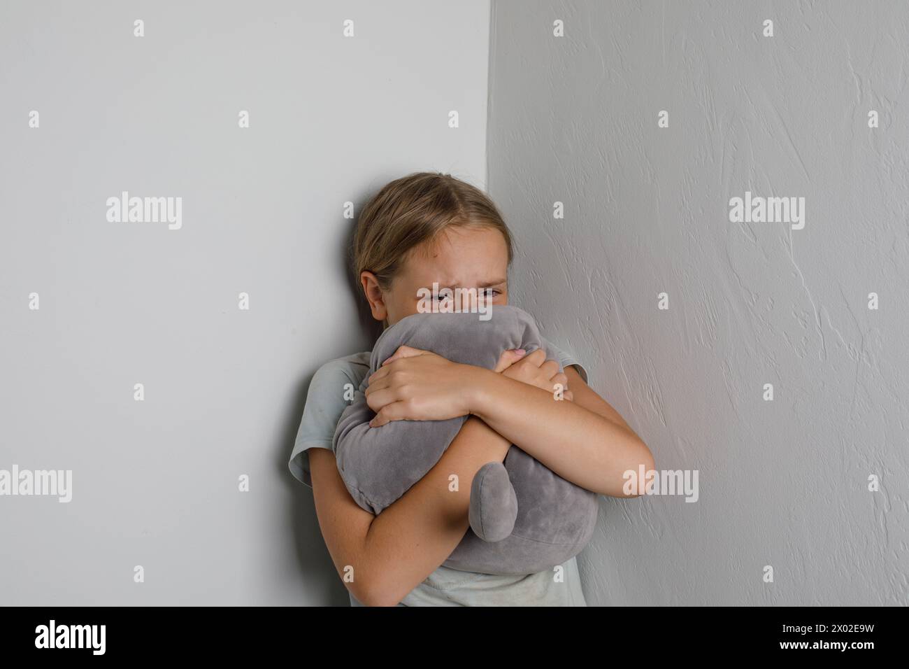 Tired young kid girl crying against white domestic wall at home Stock Photo
