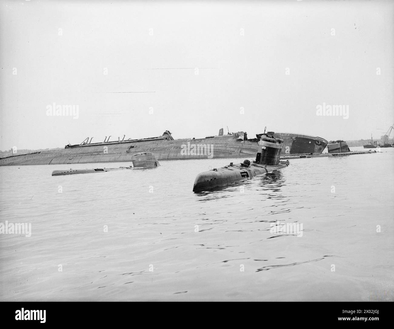 VIEWS IN KIEL AND DISTRICT. 25 MAY 1945, VARIOUS ASPECTS OF LIFE IN THE GERMAN NAVAL BASE AND TYPES OF U-BOATS USED BY THE ENEMY AS THEY WERE INSPECTED BY BRITISH SUBMARINE OFFICERS. - Scuttled type XXI ocean going electric U-boats and the bombed and sunk Hamburg-Amerika liner NEW YORK at Kiel Stock Photo
