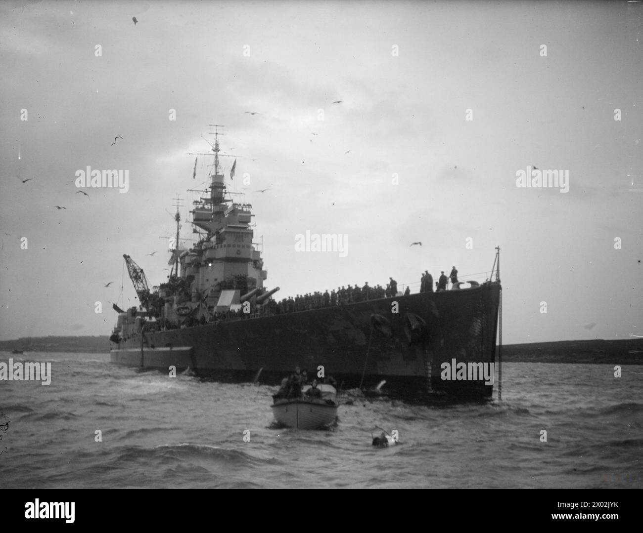 SINKING OF THE SCHARNHORST. 2 JANUARY 1944, SCAPA FLOW. ON 26 DECEMBER 1943, ONE OF GERMANY'S FEW GREAT WARSHIPS, THE 26,000 TON SCHARNHORST, WAS SUNK BY UNITS OF THE HOME FLEET. THE SCHARNHORST WAS ATTEMPTING TO INTERCEPT A RUSSIAN-BOUND CONVOY WHEN SHE WAS DRIVEN OFF, CHASED, AND FINALLY DESTROYED OFF THE NORTH CAPE. SLOWED DOWN BY TORPEDOES FROM OUR DESTROYERS, AND CRIPPLED BY GUNFIRE FROM HMS DUKE OF YORK, SHE WAS SENT TO THE BOTTOM BY TORPEDOES FIRED FROM HMS JAMAICA. - HMS DUKE OF YORK tying up  Royal Navy, HMS Dunkerton, Minesweeper, (1954) Stock Photo