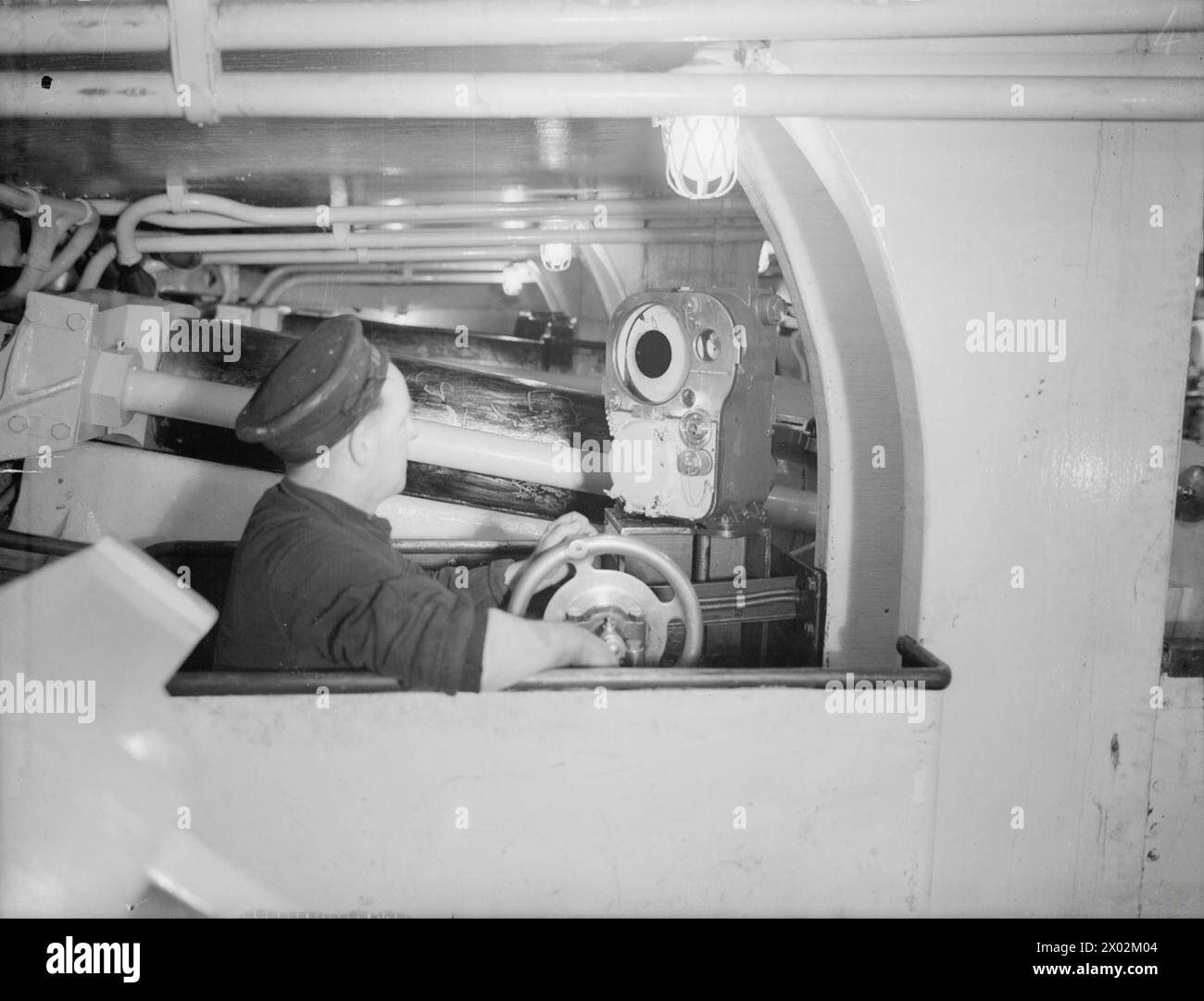 NAVAL GUNNER. APRIL 1943. - How not to lay a gun. This layer is not wearing anti-flash gear and is not keeping the pointers in line Stock Photo