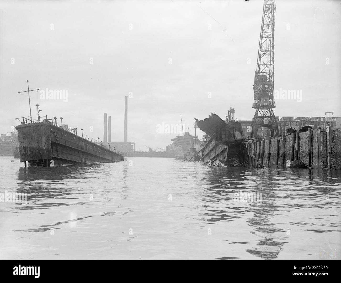 WRECKAGE IN THE BOMB-SCARRED HAMBURG DOCKS. 8 JULY 1945, WRECKED AND BURNT OUT GERMAN SHIPPING IN THE BOMB-BATTERED DOCKS AT HAMBURG. - The ROBERT LEY, 'strength through joy' ship (right), viewed through a bombed, torn and sunk floating dock Stock Photo