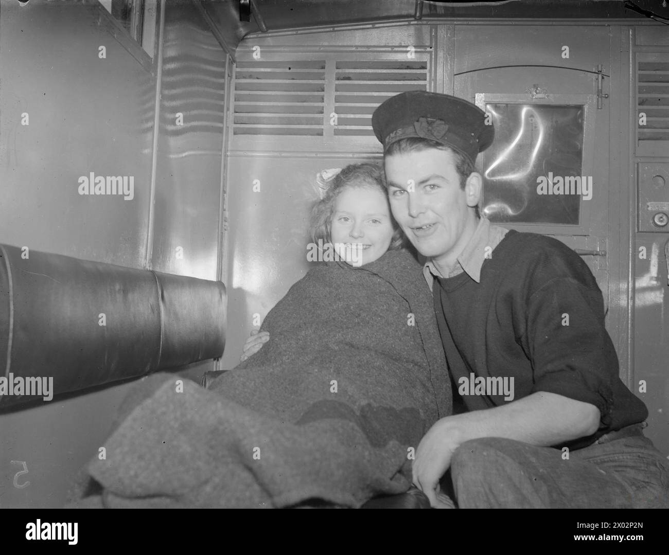 BRITISH NAVY RESCUED NORWEGIAN ISLANDERS. 27 FEBRUARY 1945, ON BOARD HMS ONSLAUGHT, AT GOUROCK. 525 NORWEGIANS, WHO HAD BEEN HIDING FROM GERMAN PATROLS IN CAVES ON THE SNOW COVERED MOUNTAINS OF SOROY ISLAND FOR THREE MONTHS, WERE RESCUED BY FOUR BRITISH DESTROYERS OF THE HOME FLEET WHO RACED IN, 60 MILES BEHIND ENEMY LINES AND TOOK THEM SAFELY TO A BRITISH PORT (GOUROCK). - A Norwegian girl with both arms broken, in the ambulance with the sailor who carried her there Stock Photo