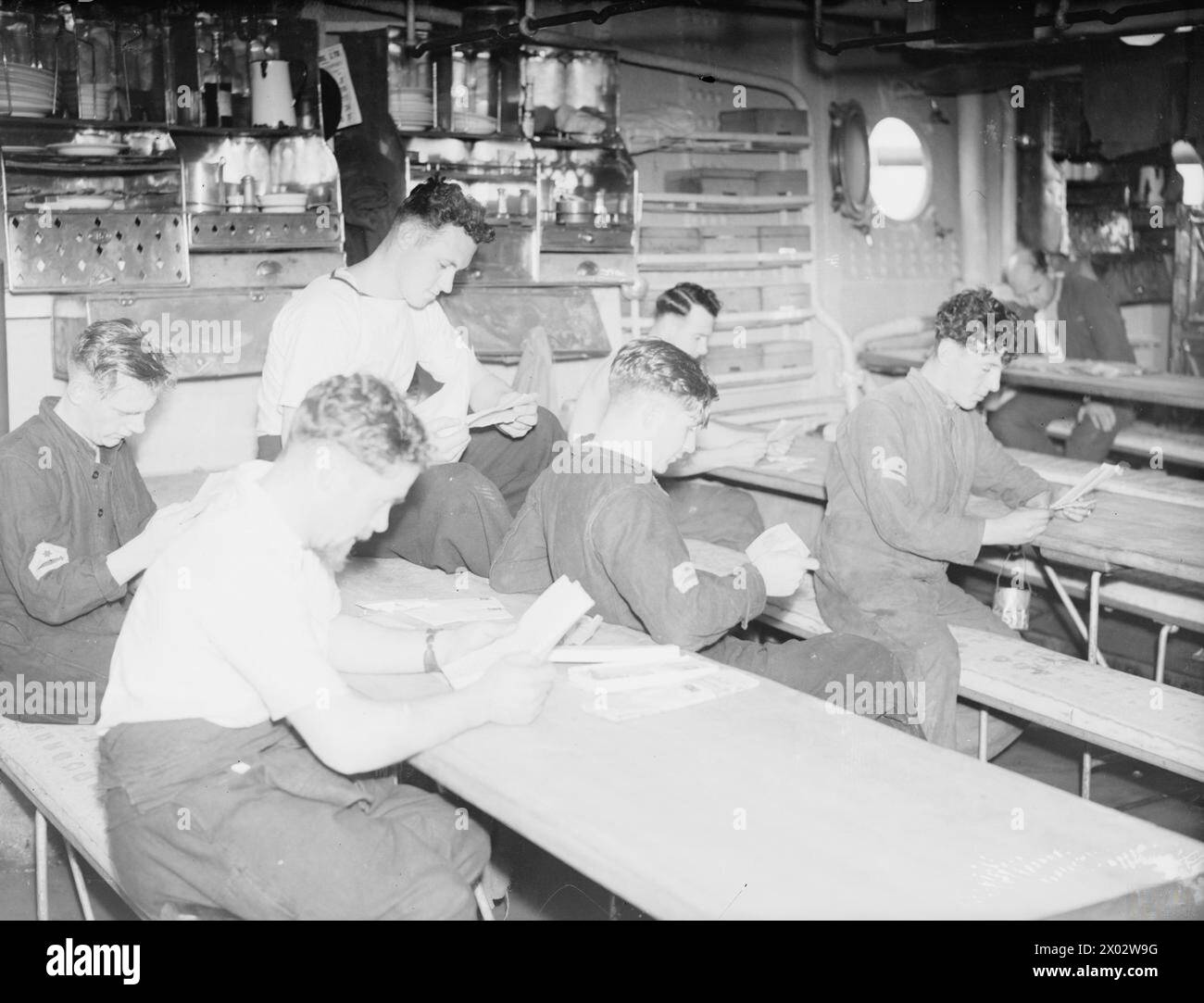 MAIL. 1940, ON BOARD THE BRITISH BATTLESHIP HMS RODNEY. - Reading the news from home. Many of the men receive news of additions to their families Stock Photo