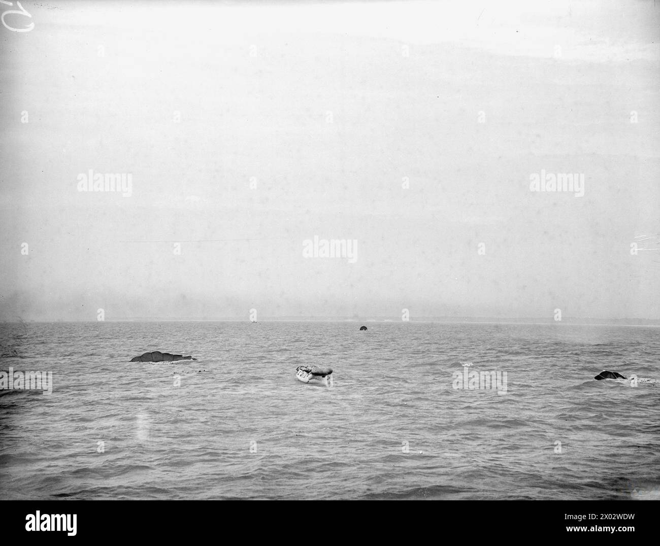 LIFEBOAT DROPPED FROM AIR. 13 JULY 1945, LEE-ON-SOLENT. THE DEMONSTRATION DROP OF THE NAVY'S AIRBORNE LIFEBOAT, 17 FT, 9 INS LONG, WHEN IT WAS DROPPED BY PARACHUTE TO AN AIR CREW WHO WERE SUPPOSED TO HAVE FORCED LANDED INTO THE SEA. THE LIFEBOAT, SELF-RIGHTING, AND SELF-BALING IS EQUIPPED WITH SAILS AND AN OUTBOARD ENGINE WHICH GIVES IT A RANGE OF 120 MILES AT 4 KNOTS. - The lifeboat and parachutes in the sea Stock Photo