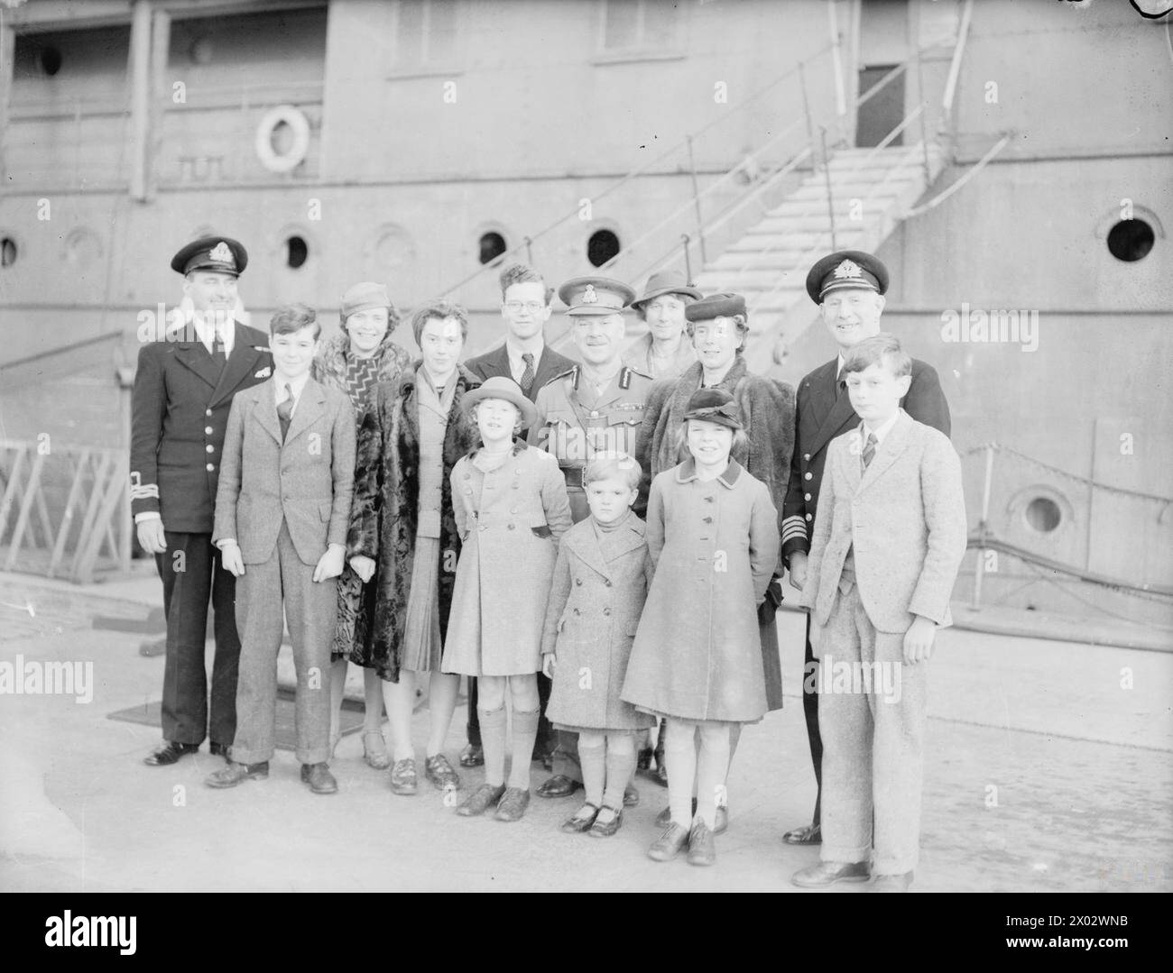 DISTINGUISHED COMPANY VISIT HMS COCHRANE AT ROSYTH. 25 DECEMBER 1941. - Left to right: Lieut Cdr Reid, RNVR, of HMS COCHRANE; Lord Jamie Bruce; Miss Don; Lady Jean Bruce; Lord Bruce, Earl of Elgin; Lady Cochrane (behind); The Countess of Elgin (in black hat and coat); Captain C H G Benson, DSO, RN. Front, Left to right: Miss Cochrane; Lord David Bruce, Lady Alison Bruce, and Master Cochrane Stock Photo