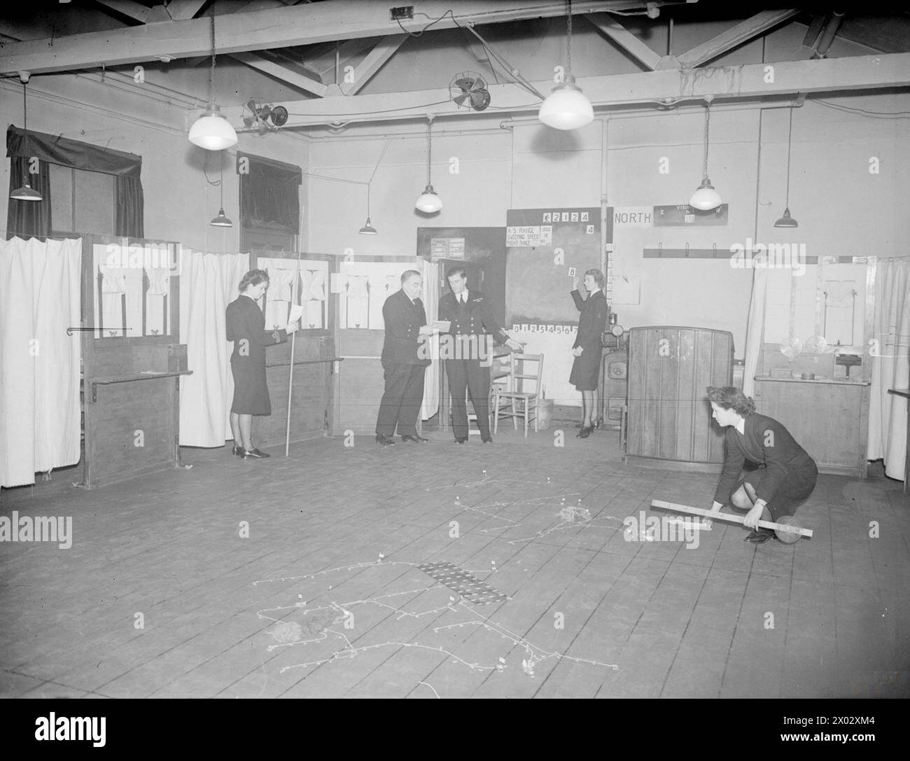 THE WESTERN APPROACHES TACTICAL UNIT, WHERE THE PROBLEMS OF ANTI-U-BOAT WARFARE ARE FOUGHT OUT. 18 MARCH 1945, DERBY HOUSE, LIVERPOOL. AT A ONE WEEK TACTICAL COURSE, COMMANDING, AND OTHER OFFICERS OF BRITISH AND ALLIED ESCORT VESSELS 'PLAYED GAMES' WHICH ENABLED THEM TO COMBAT THE U-BOAT MENACE. ANTI-U-BOAT OPERATIONS WERE PLOTTED AND CARRIED OUT ON TACTICAL TABLES BY GROUPS OF OFFICERS COMPETING AGAINST EACH OTHER. WHEN THE PLAY WAS ALL OVER THE ACTION TAKEN BY EACH GROUP WAS VIEWED BY ALL, AND RE-PLAY AND CRITICISMS TOOK PLACE. - The Tactical Table ready for the next move. Here the inside of Stock Photo