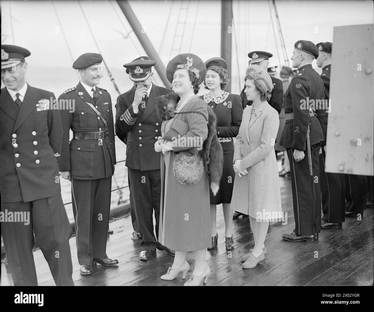 ROYAL VISIT TO HMS KING GEORGE V. 29 OCTOBER 1944, GREENOCK. THE KING AND QUEEN ACCOMPANIED BY PRINCESS ELIZABETH AND PRINCESS MARGARET PAID A FAREWELL VISIT TO THE BATTLESHIP HMS KING GEORGE V BEFORE SHE LEFT TO JOIN BRITAIN'S EAST INDIES FLEET. - The Queen and the Princesses watching ammunition being brought on board the battleship Stock Photo