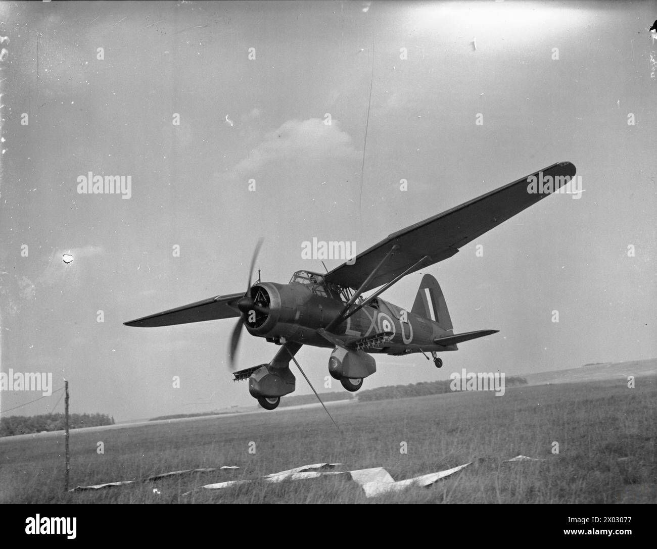NO. 22 (ARMY CO-OPERATION) GROUP, ROYAL AIR FORCE, JUNE-NOVEMBER 1940. - Westland Lysander Mark II, R2007 'LX-U', of No. 225 Squadron RAF deploys its ventral message hook for an in-flight pick-up during a training flight at Tilshead, Wiltshire. R2007 subsequently flew with a number of units, including Nos. 13 and 2 Squadrons RAF, No. 7 Anti-aircraft Cooperation Unit, No. 239 Squadron RAF, and in the Far East with both Nos. 1 and 2 Squadrons of the Indian Air Force. The aircraft was finally written off after a heavy landing at Risalpur on 16 March 1943, while serving with No, 151 (Fighter) Oper Stock Photo