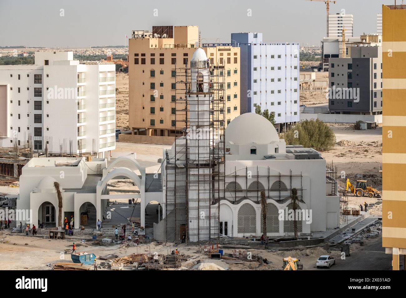 JANABIYA, BAHRAIN - 20 MAY, 2018: Workmen on a mosque under construction against a backdrop of apartment blocks. Stock Photo