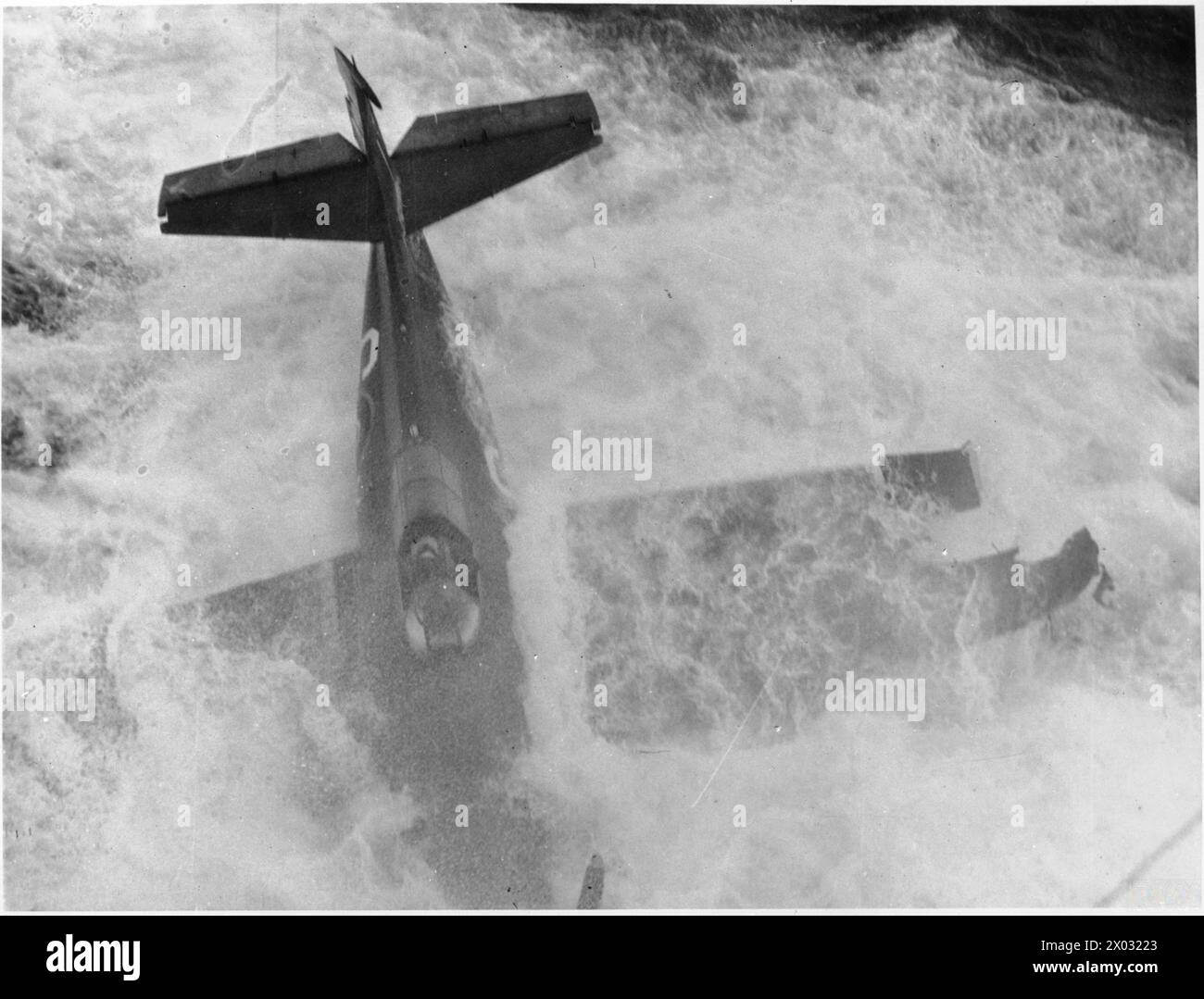 THE ROYAL NAVY DURING THE SECOND WORLD WAR - A wrecked Grumman Wildcat, with the port wing damaged, caught in the wash of the carrier after the plane had swung when taking off and had gone over the side of a British Escort Carrier, probably HMS SEARCHER. The pilot appears to be still in the aircraft cockpit  Royal Navy, SEARCHER (HMS) Stock Photo