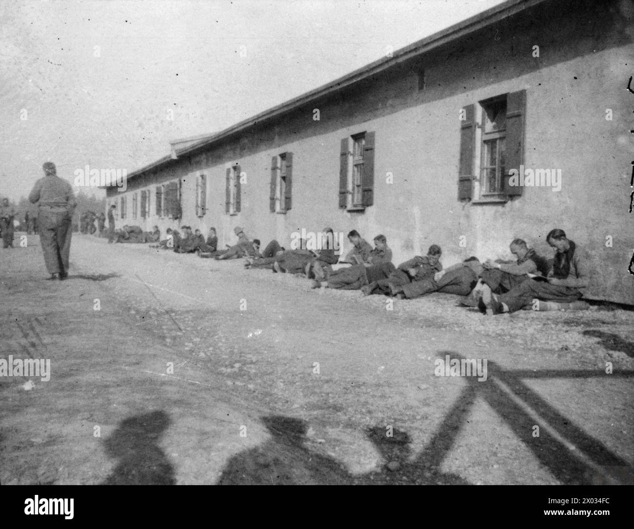 THE BRITISH ARMY IN NORTH-WEST EUROPE 1944-45 - A photograph taken covertly at Stalag VIIA at Mooseburg in November 1943, showing British POWs resting by the side of a hut Stock Photo
