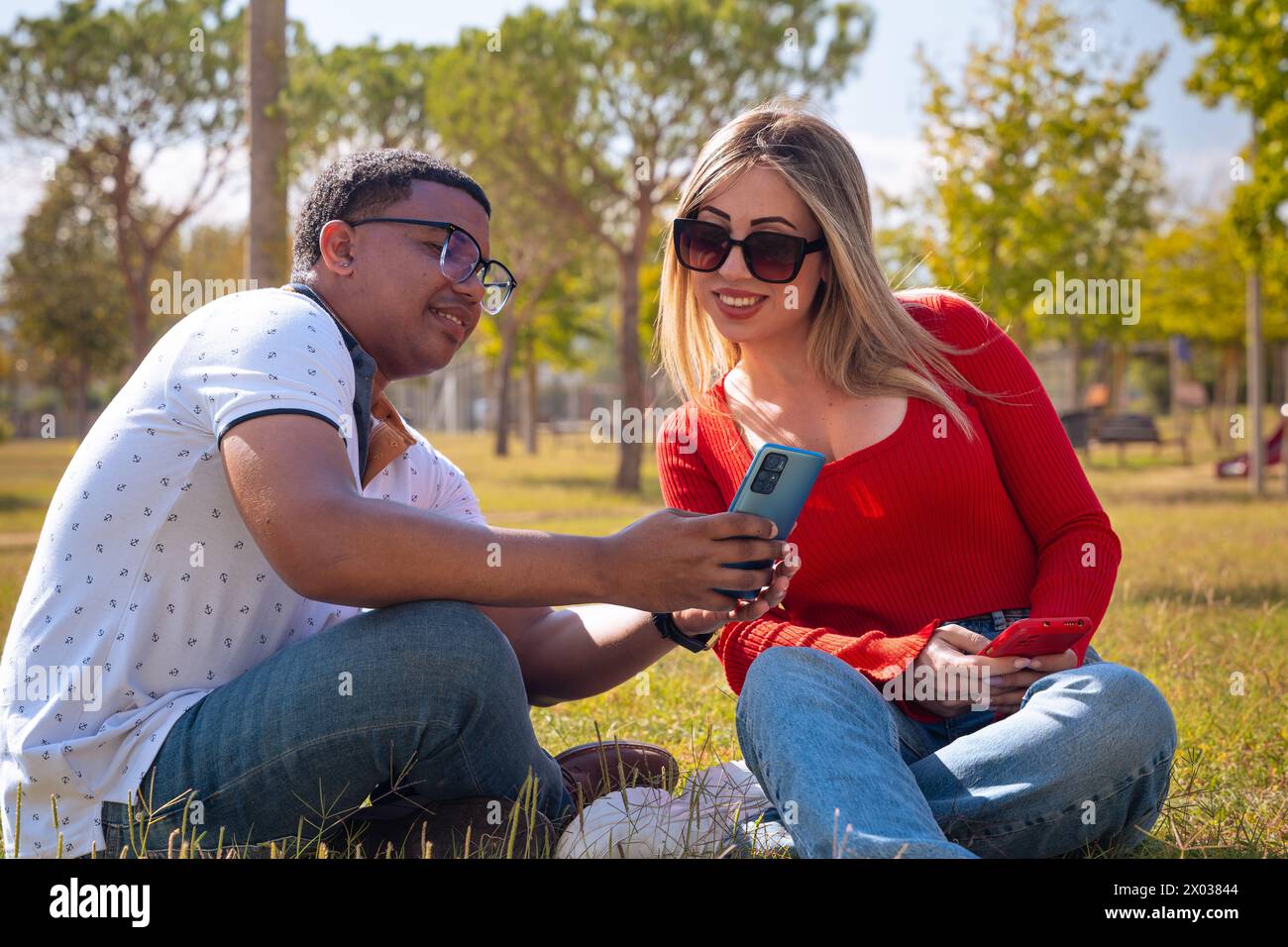 Happy interracial couple checking cell phone outdoors. Stock Photo